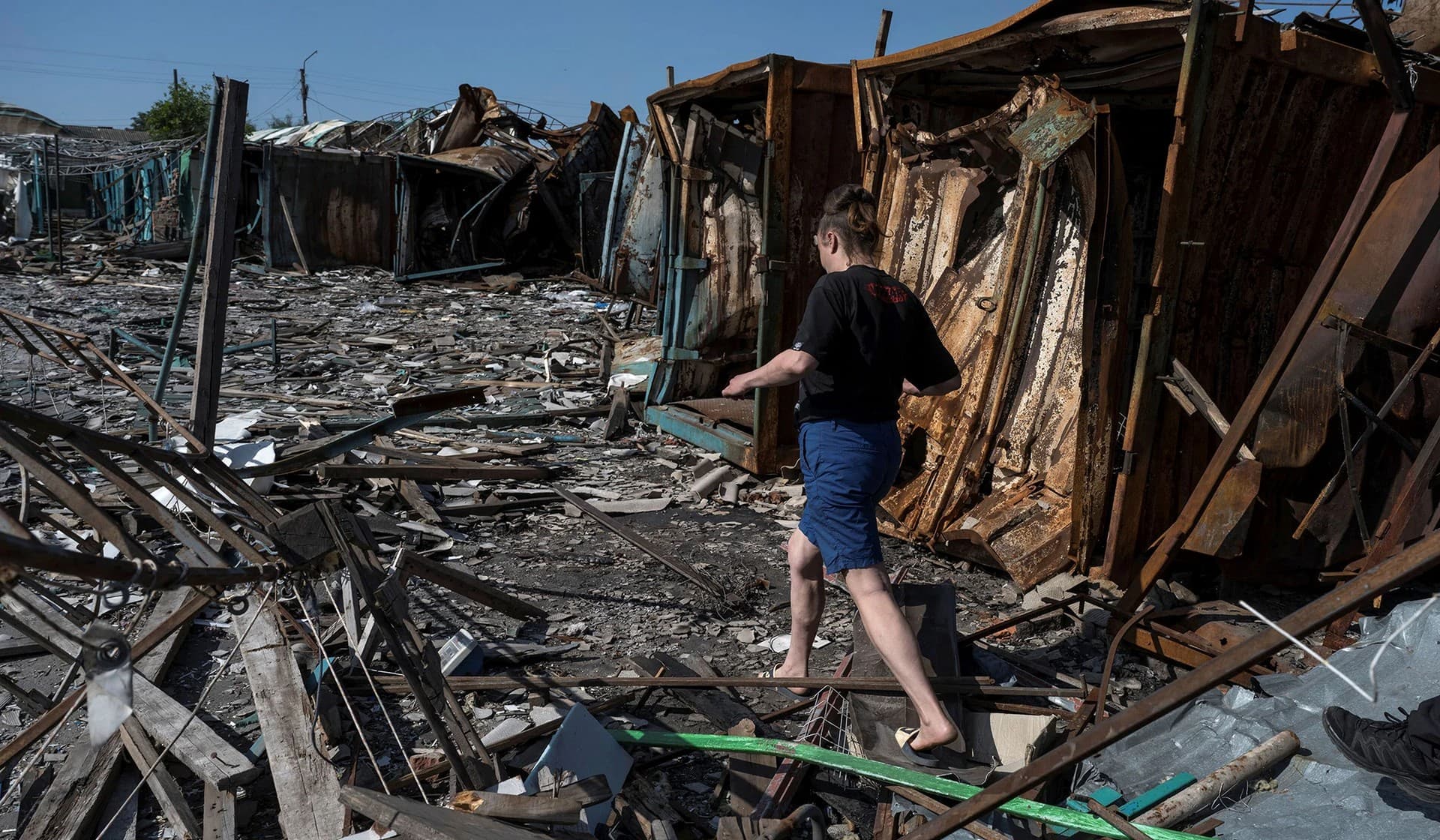 A local walks at a compound of a municipal market destroyed by a Russian military strike in the border town of Vovchansk