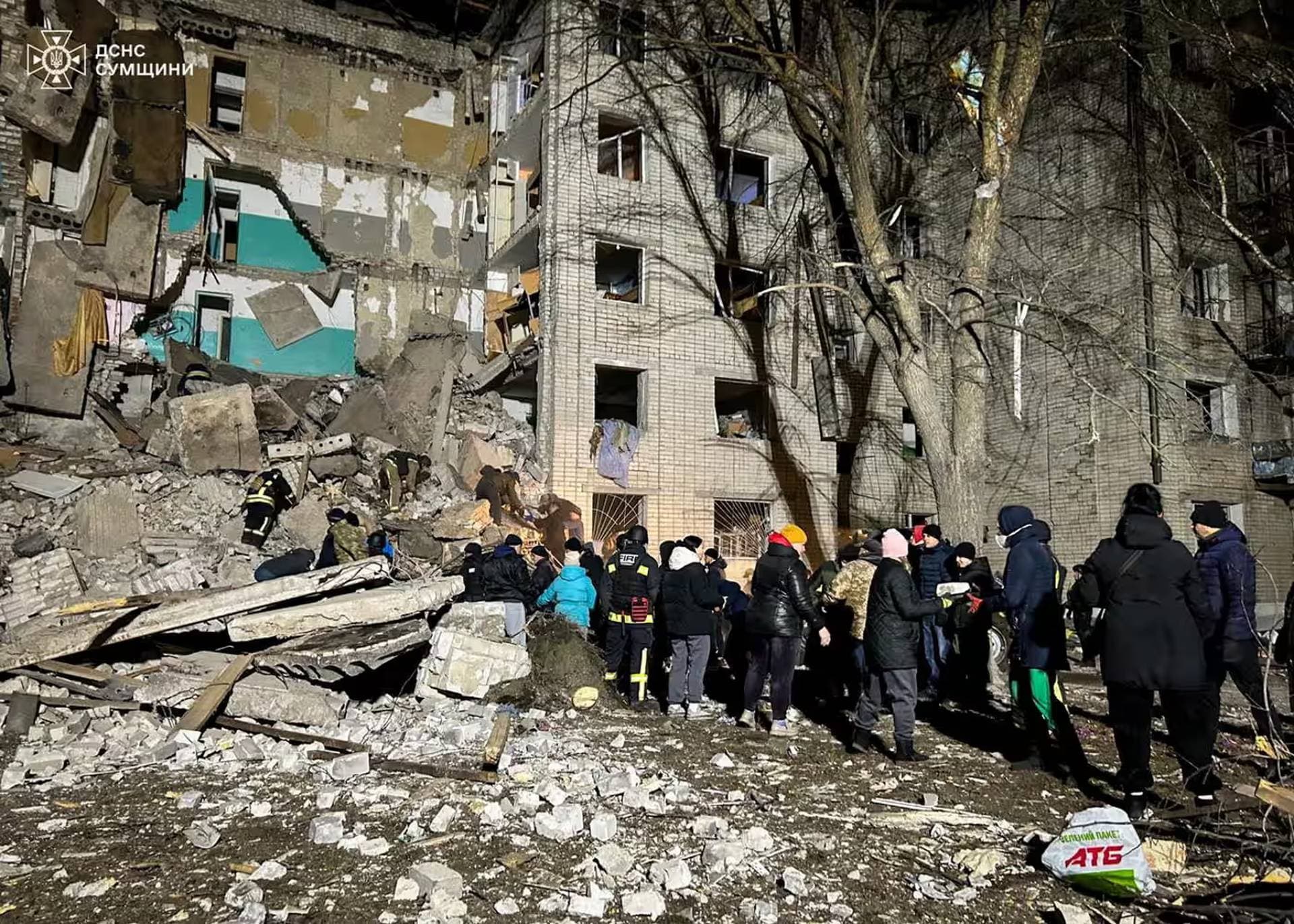 Rescuers and volunteers remove debris at the site of a residential building hit by a Russian drone strike in Hlukhiv