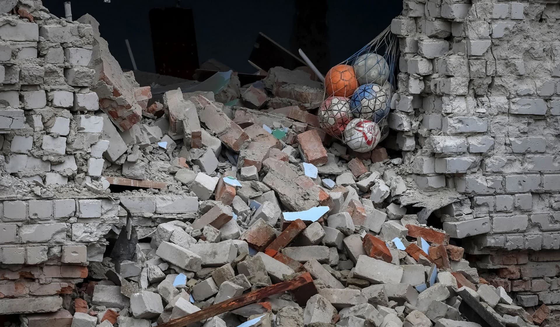 Soccer balls sit in the ruins of a destroyed school building in the village of Verbivka
