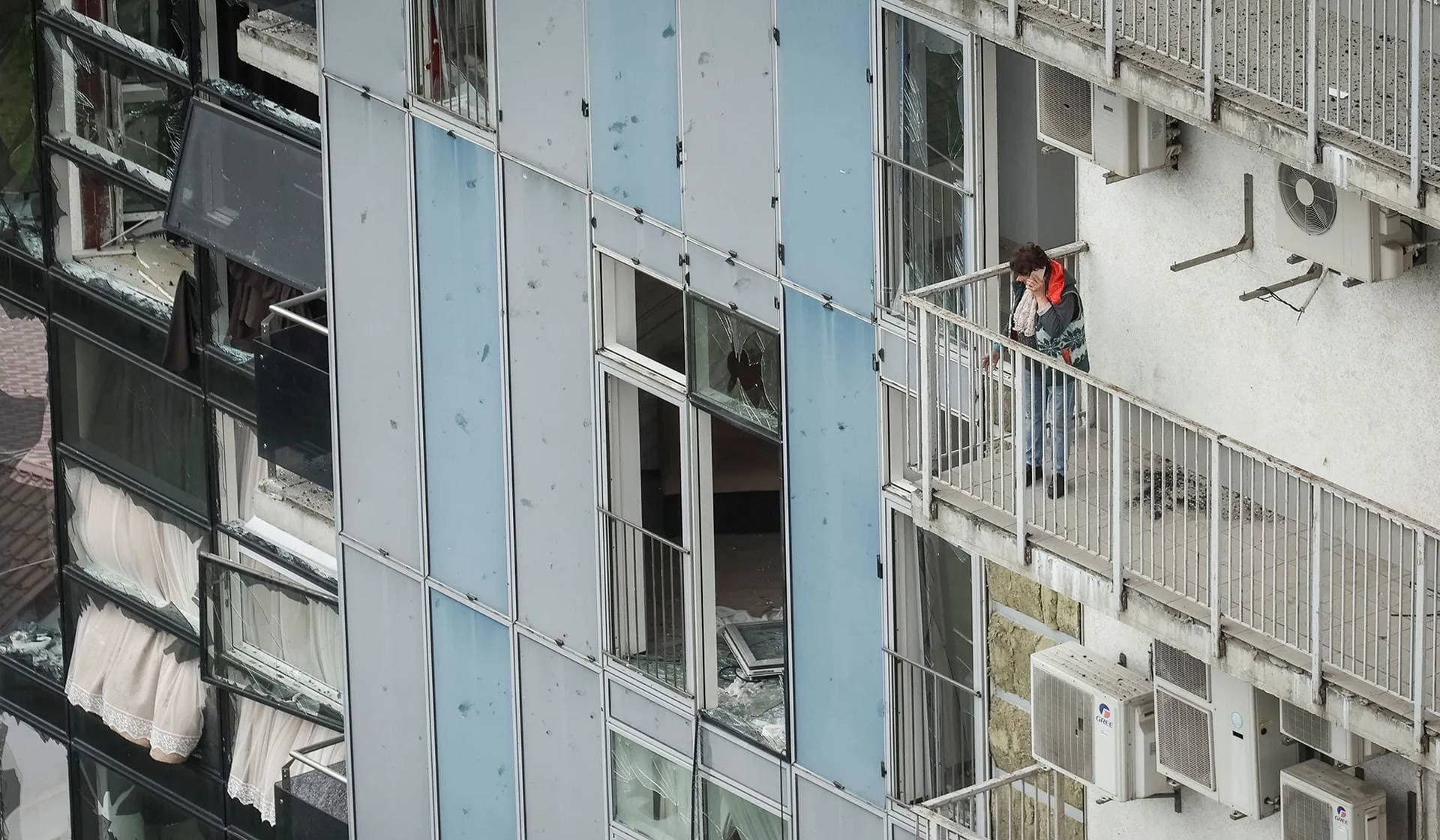 A local resident stands on the balcony of an apartment building damaged by a Russian missile strike in Kharkiv