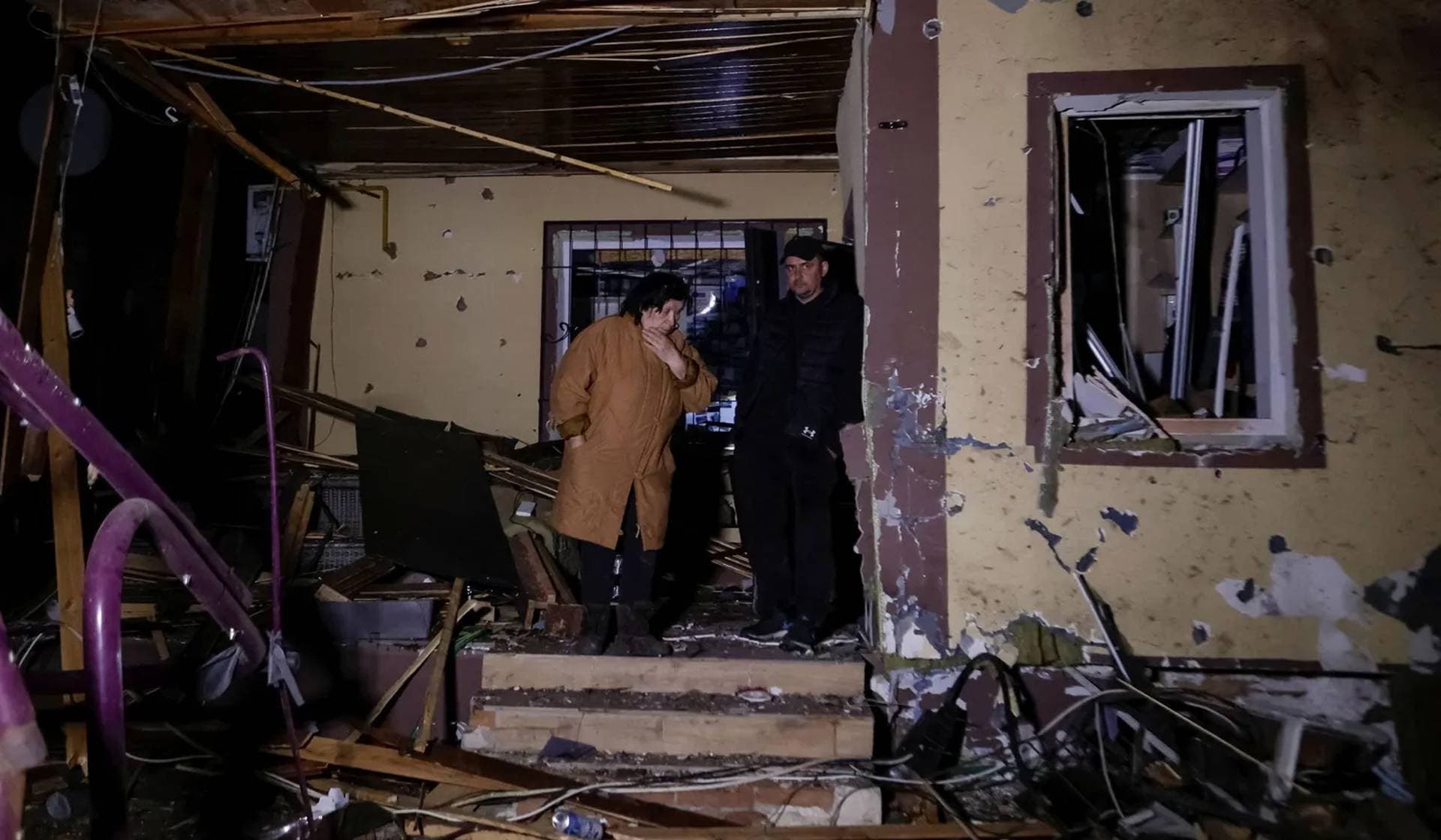 Residents stand near a building damaged by a Russian drone strike in Kharkiv