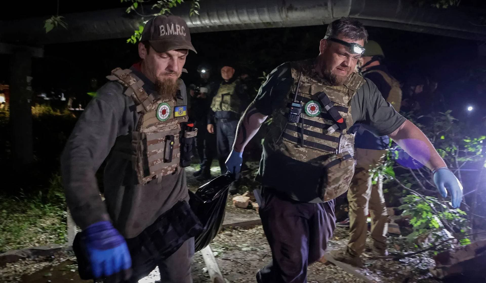 Rescuers carry the body of a person killed in a Russian missile strike at the site of a residential building which was hit in the strike in Kharkiv