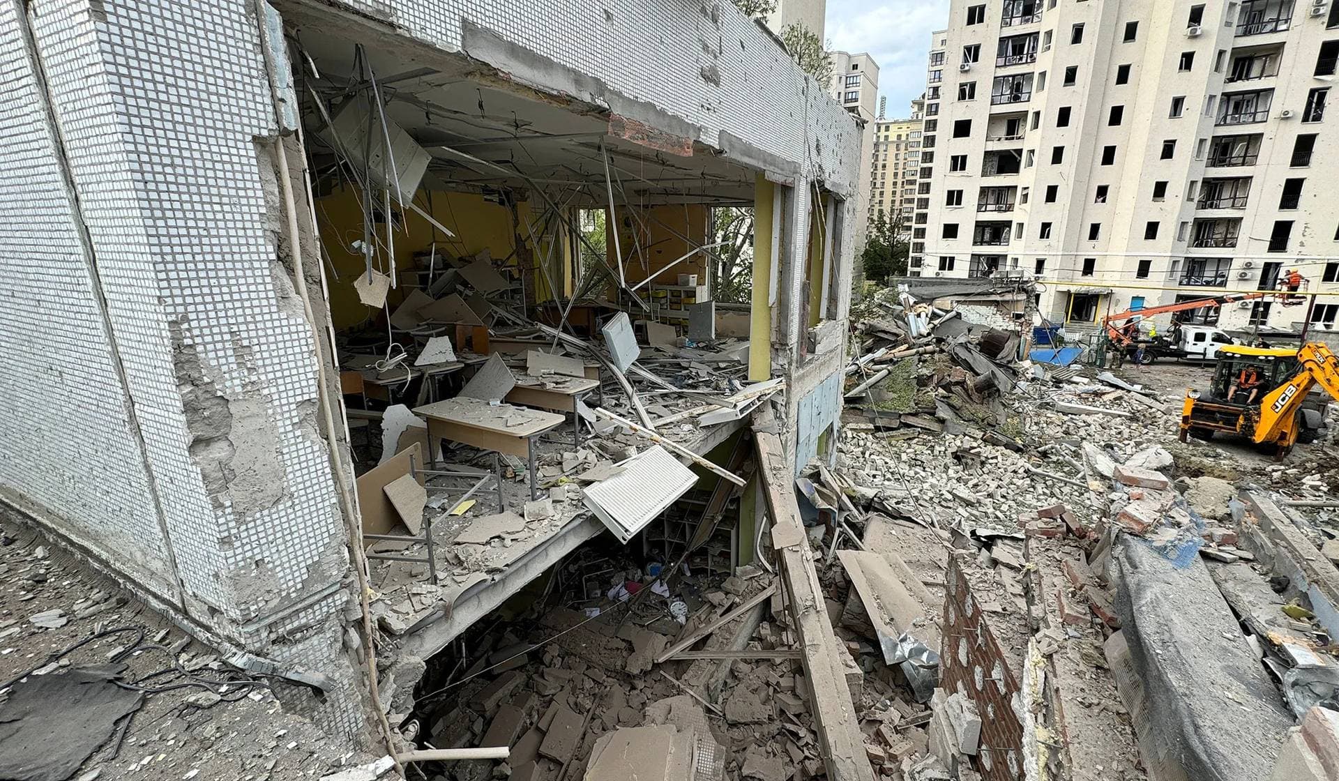 A damaged apartment building and a destroyed school at the site of a Russian air strike in Kharkiv