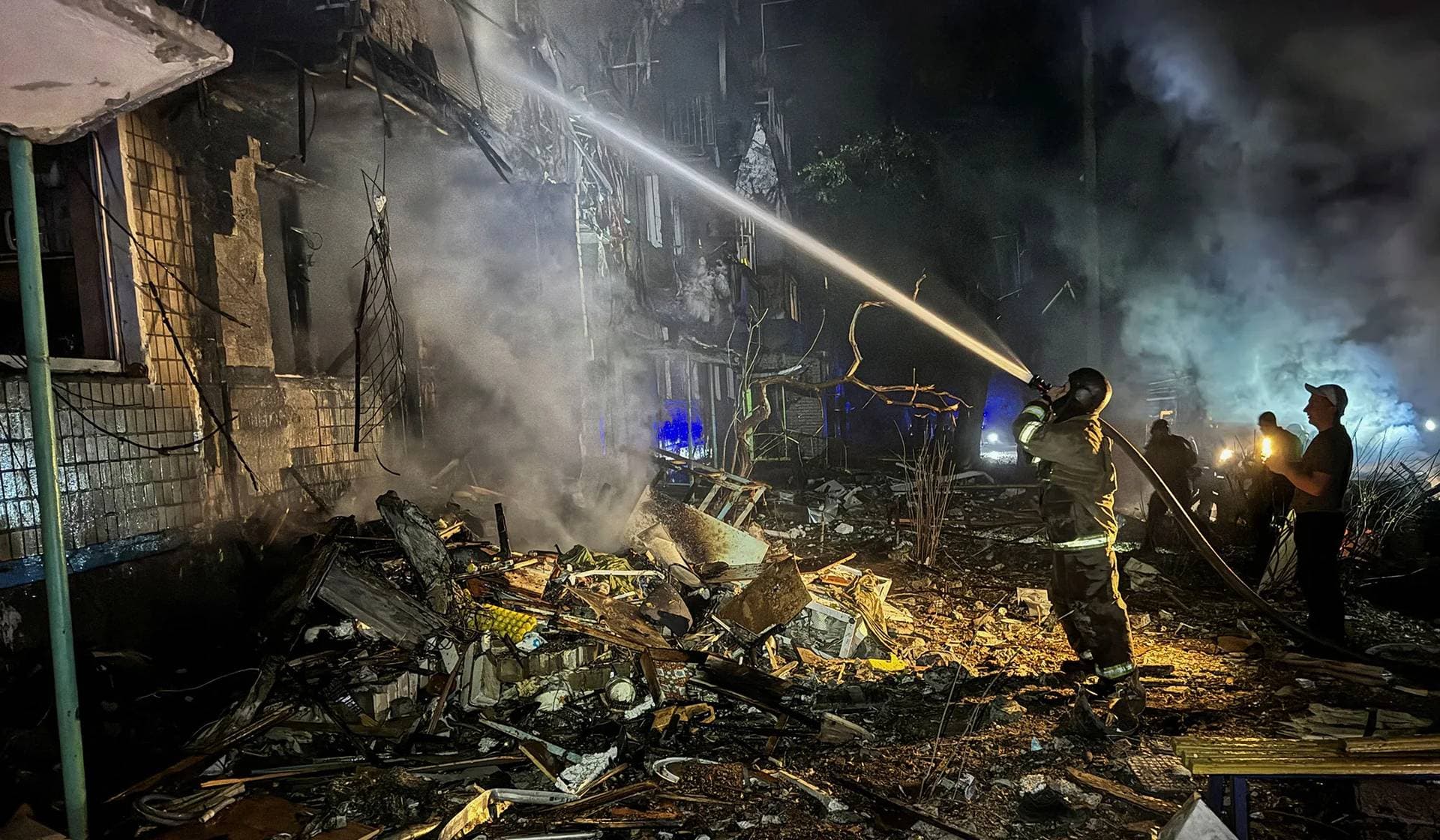 A firefighter works at a site of an apartment building hit by a Russian air strike in Kharkiv