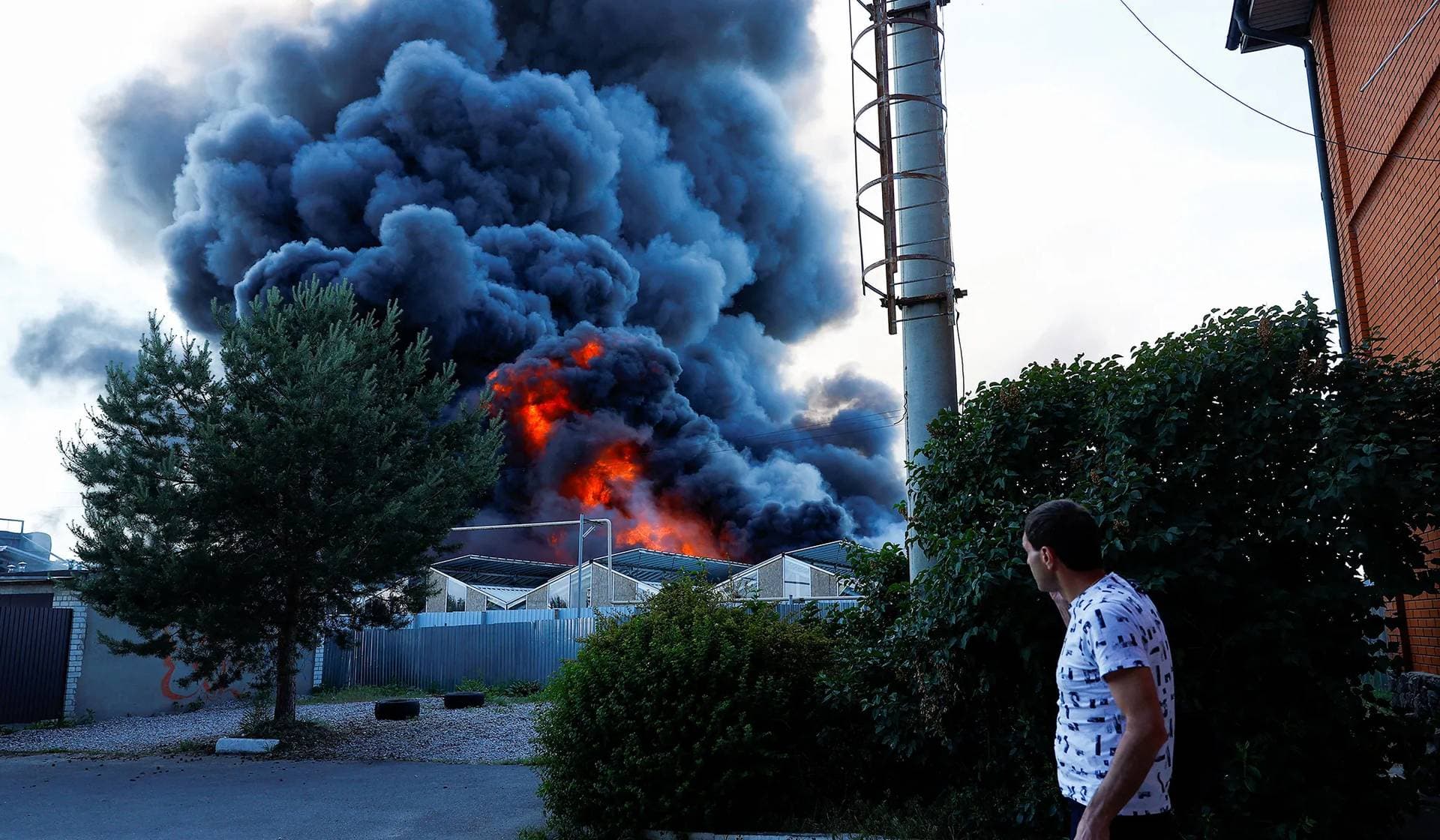 A man watches as smoke rises from a household item shopping mall hit by a Russian air strike in Kharkiv