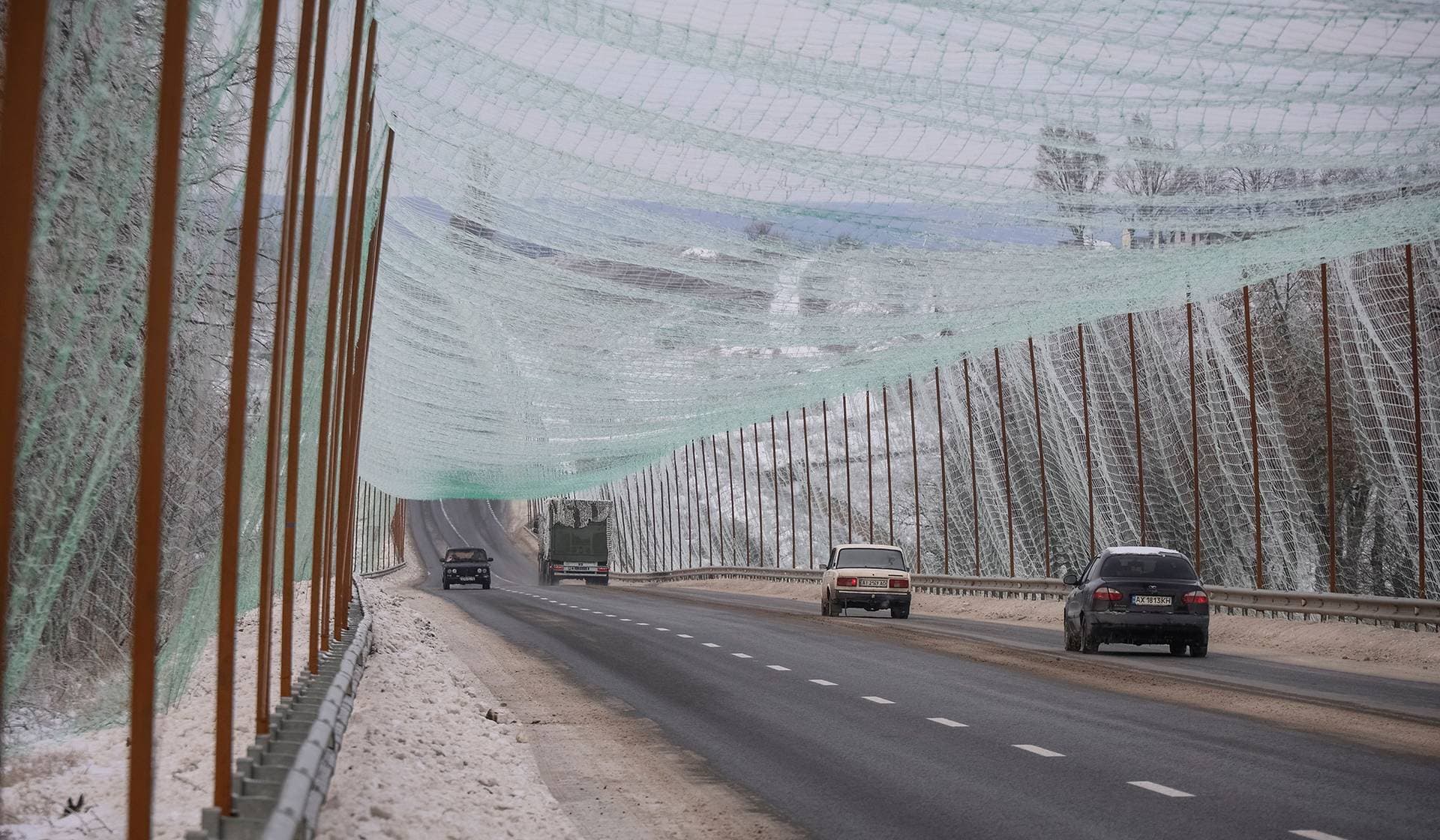 Cars drive along a road covered with an newly installed anti-drone net near Kharkiv