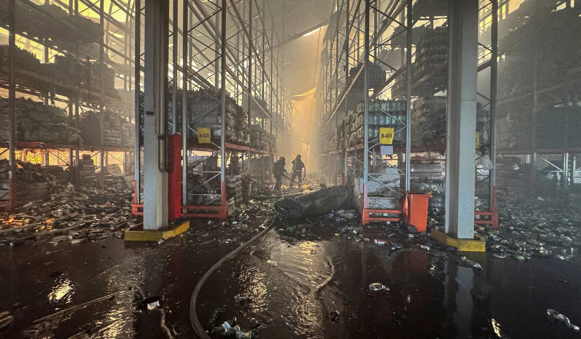 Firefighters work inside a food warehouse hit by a Russian military strike in the village of Vasyshcheve outside Kharkiv