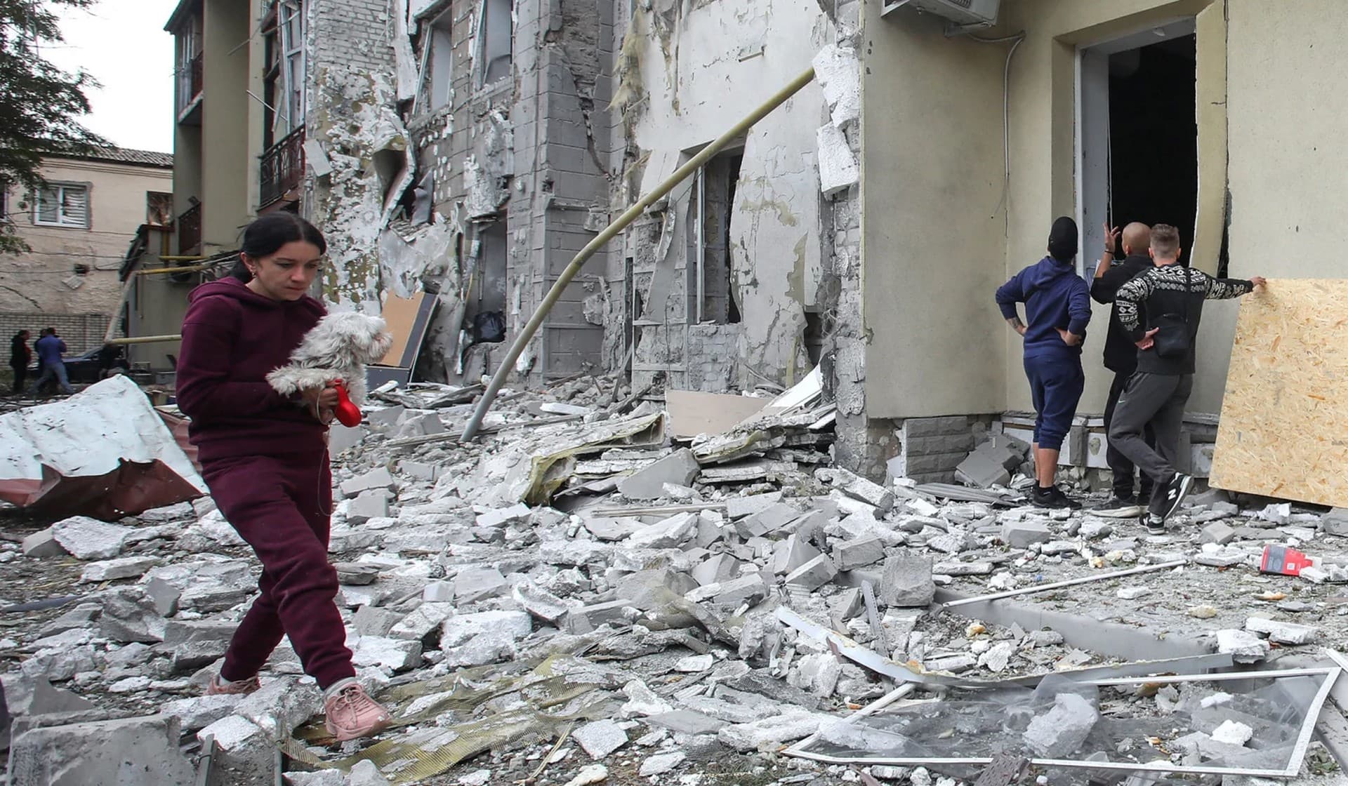 A woman carries a dog in a front of a residential building damaged by a Russian missile strike in Kharkiv