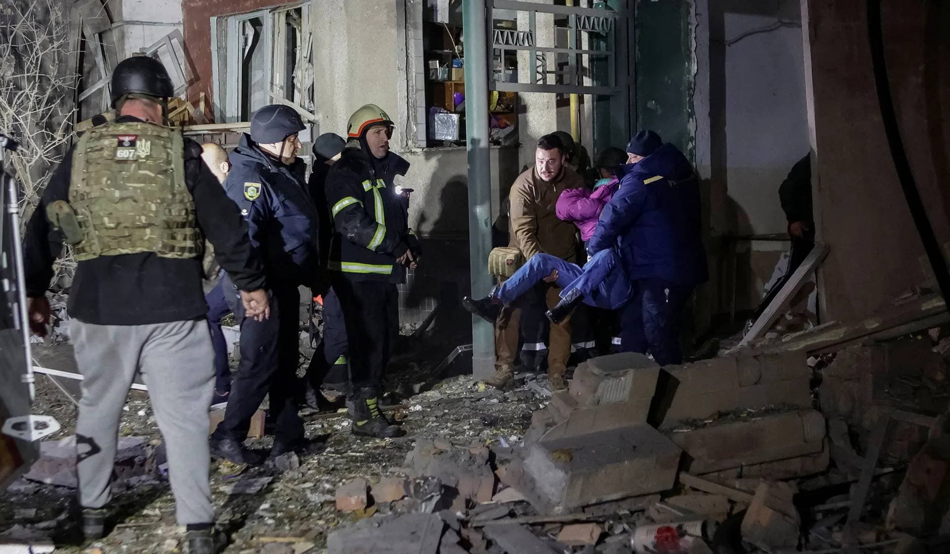 Rescuers and medical workers carry a survivor at the site of an apartment building hit by a Russian air strike in Kharkiv