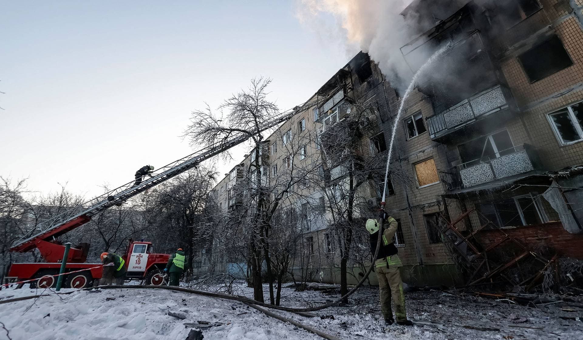 Firefighters work at the site of the apartment building hit by a Russian drone strike in Kharkiv