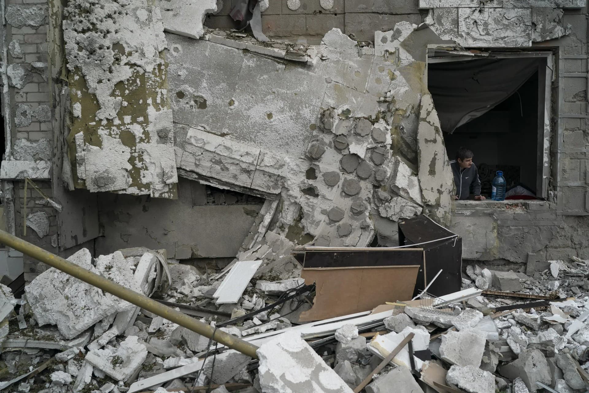 A man looks out from a window of a residential building that was damaged after a Russian attack in Kharkiv