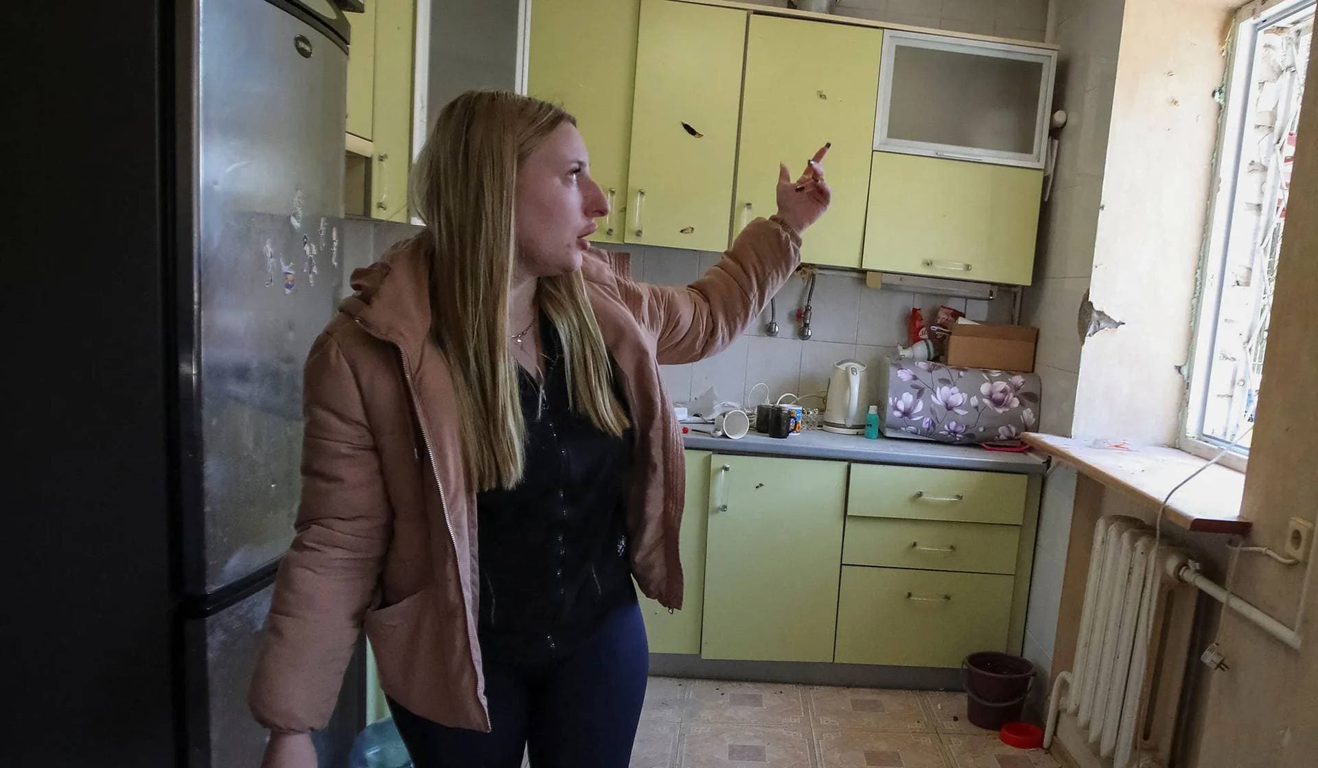 Local resident shows her apartment damaged by a Russian military strike in Kharkiv