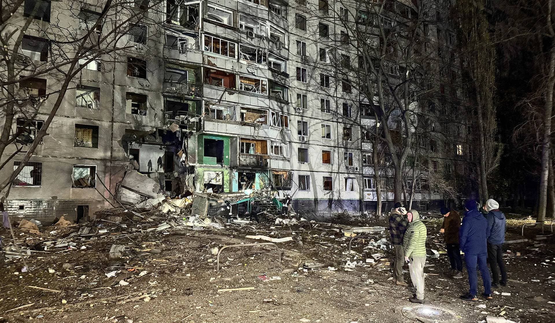 Residents stand next to their apartment building hit by a Russian air strike in Kharkiv