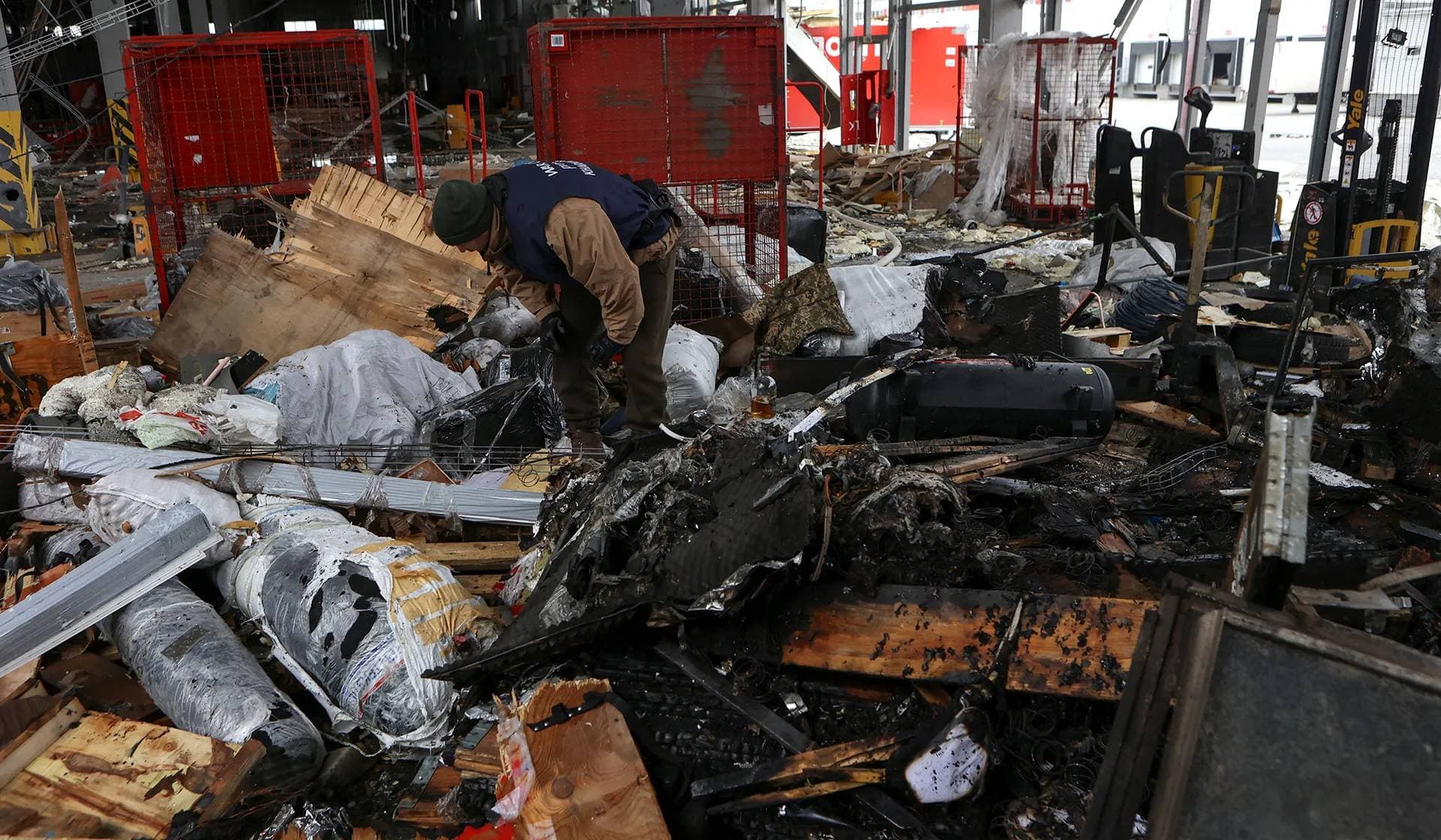 A war-crime prosecutor works at a site of a postal distribution center of Nova Post company, hit by Russian missiles, in the village of Korotych outside Kharkiv