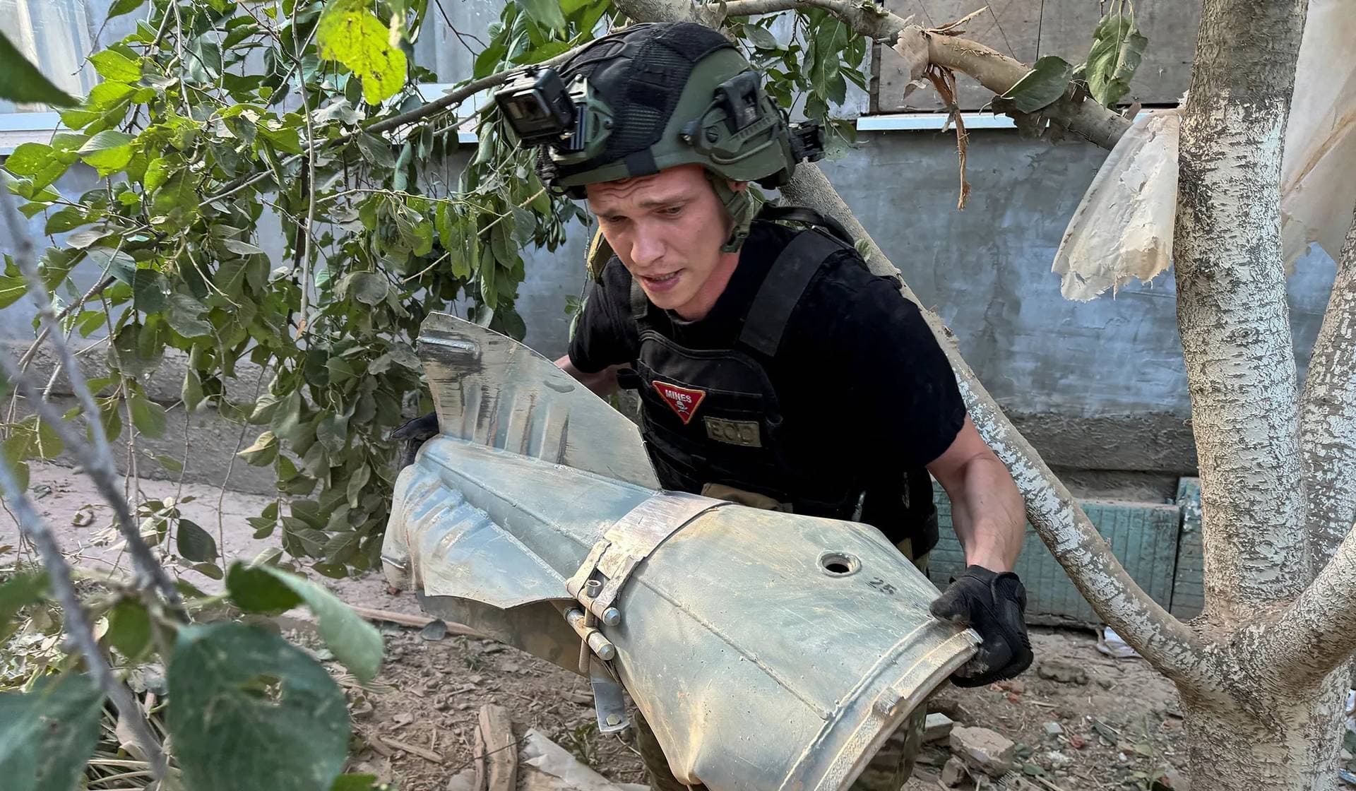 A police bomb squad member carries a part of a Russian glide bomb near a private house hit by a Russian air strike in Kharkiv