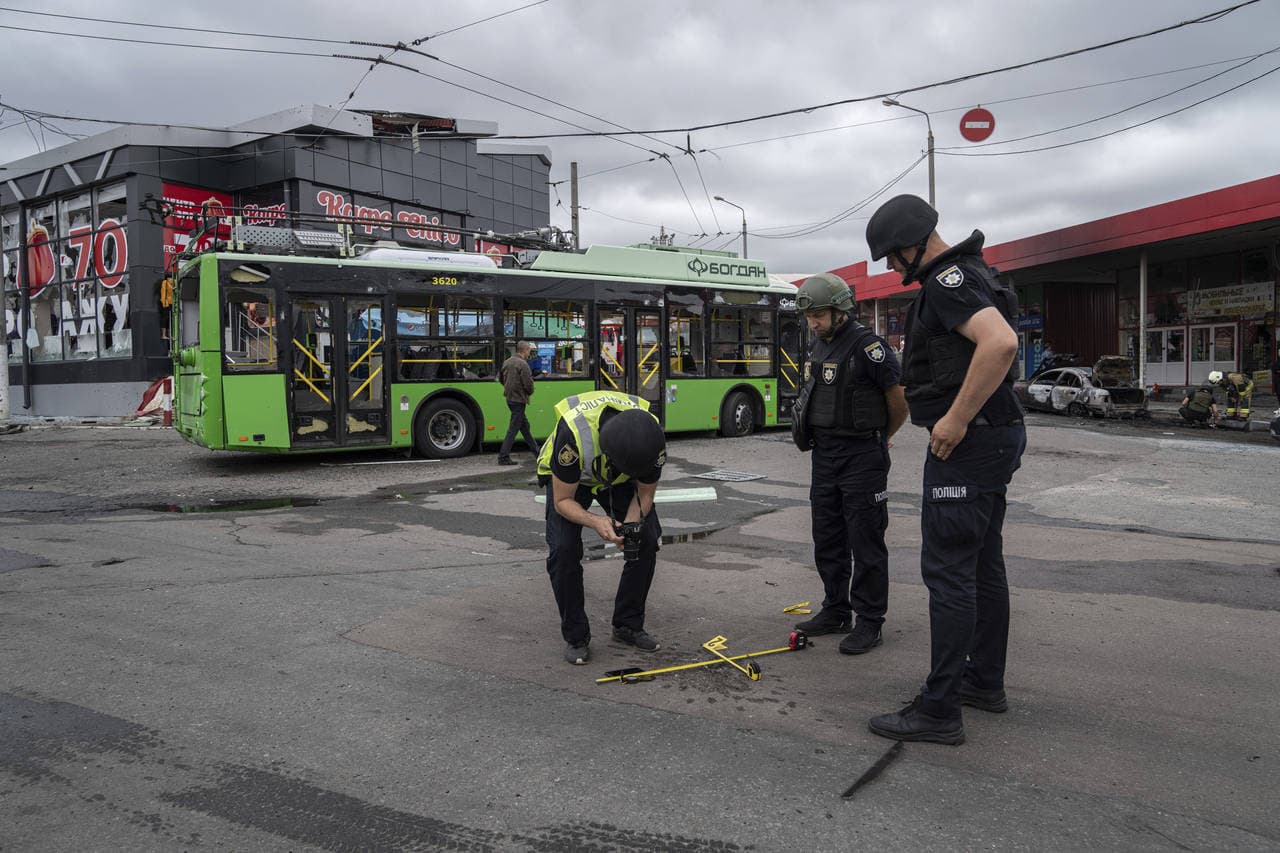 Police officers examine a small crater after a Russian shelling at Barabashovo market in Kharkiv