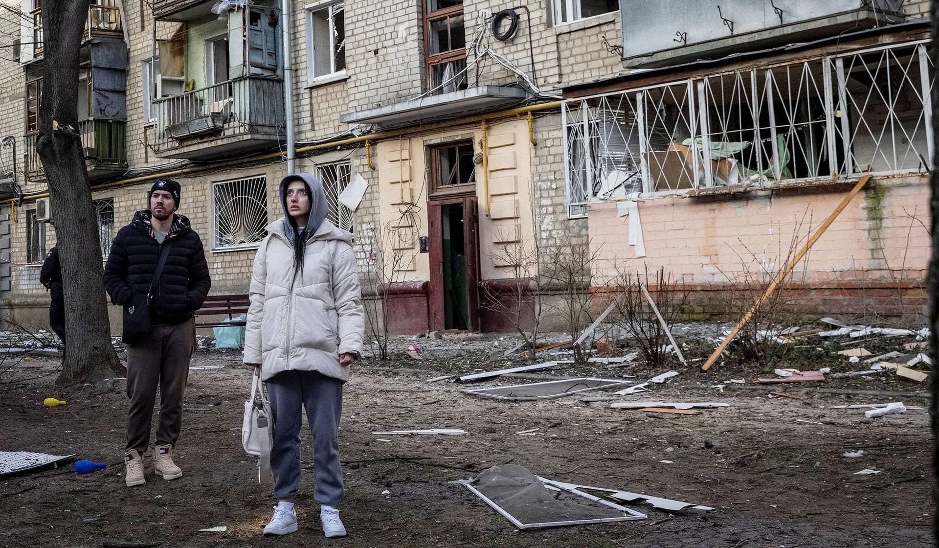 Local residents stand at the site where buildings were damaged by a Russian military strike in Kharkiv