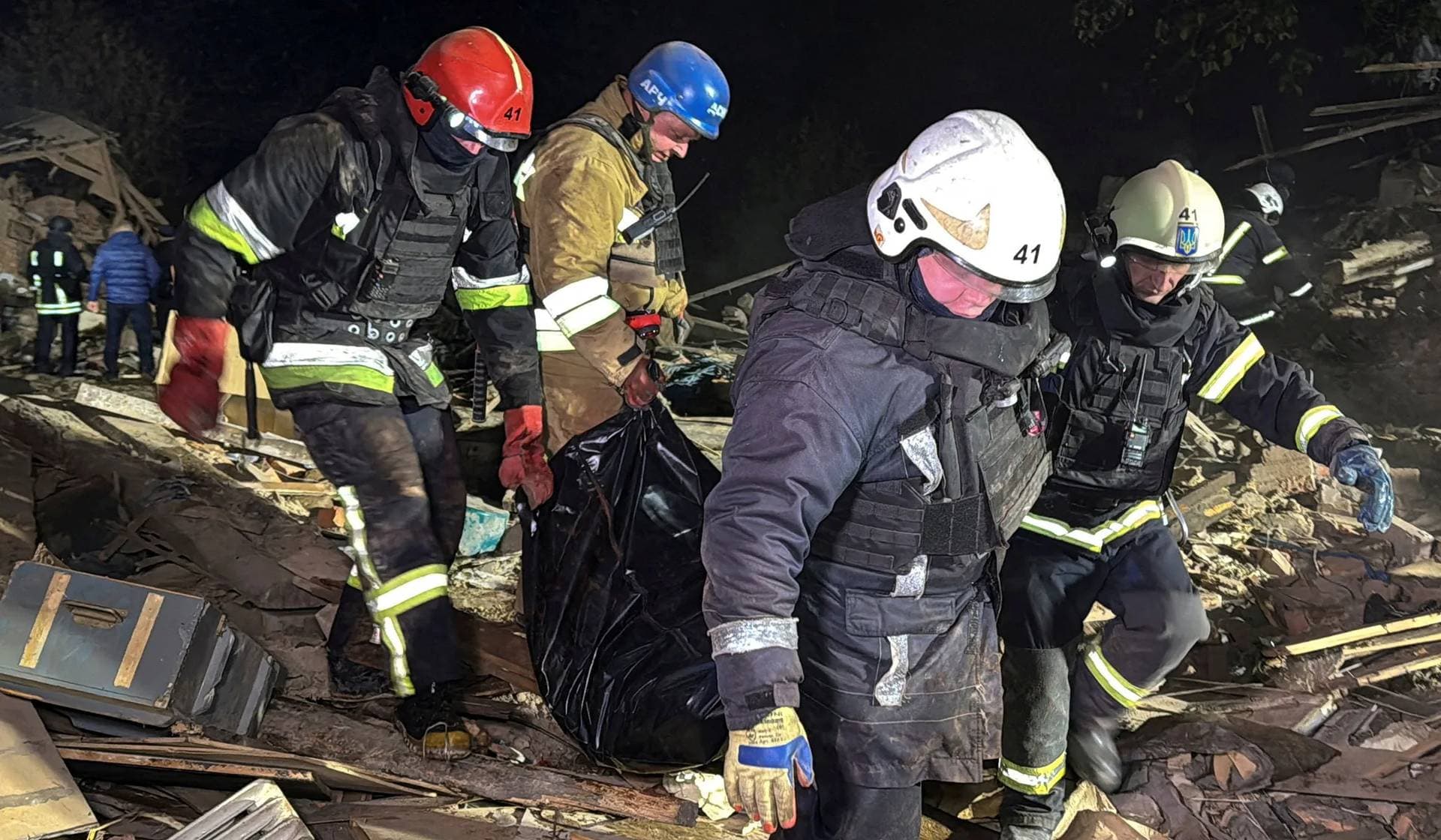 Rescuers carry the body of a person found under debris of a private house which was hit by a Russian missile strike in Kharkiv
