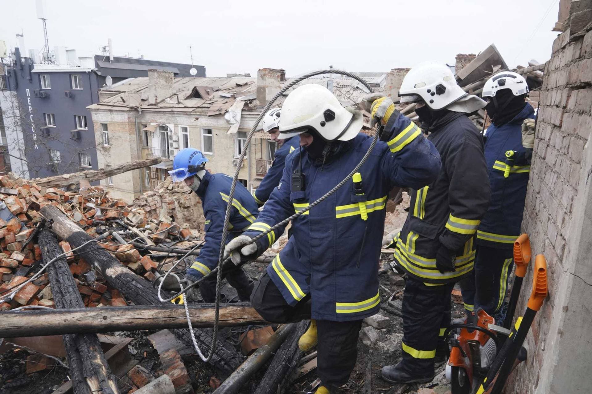 Ukrainian emergency workers clear the rubble on the roof of a residential building which was hit by a Russian rocket at the city center of Kharkiv