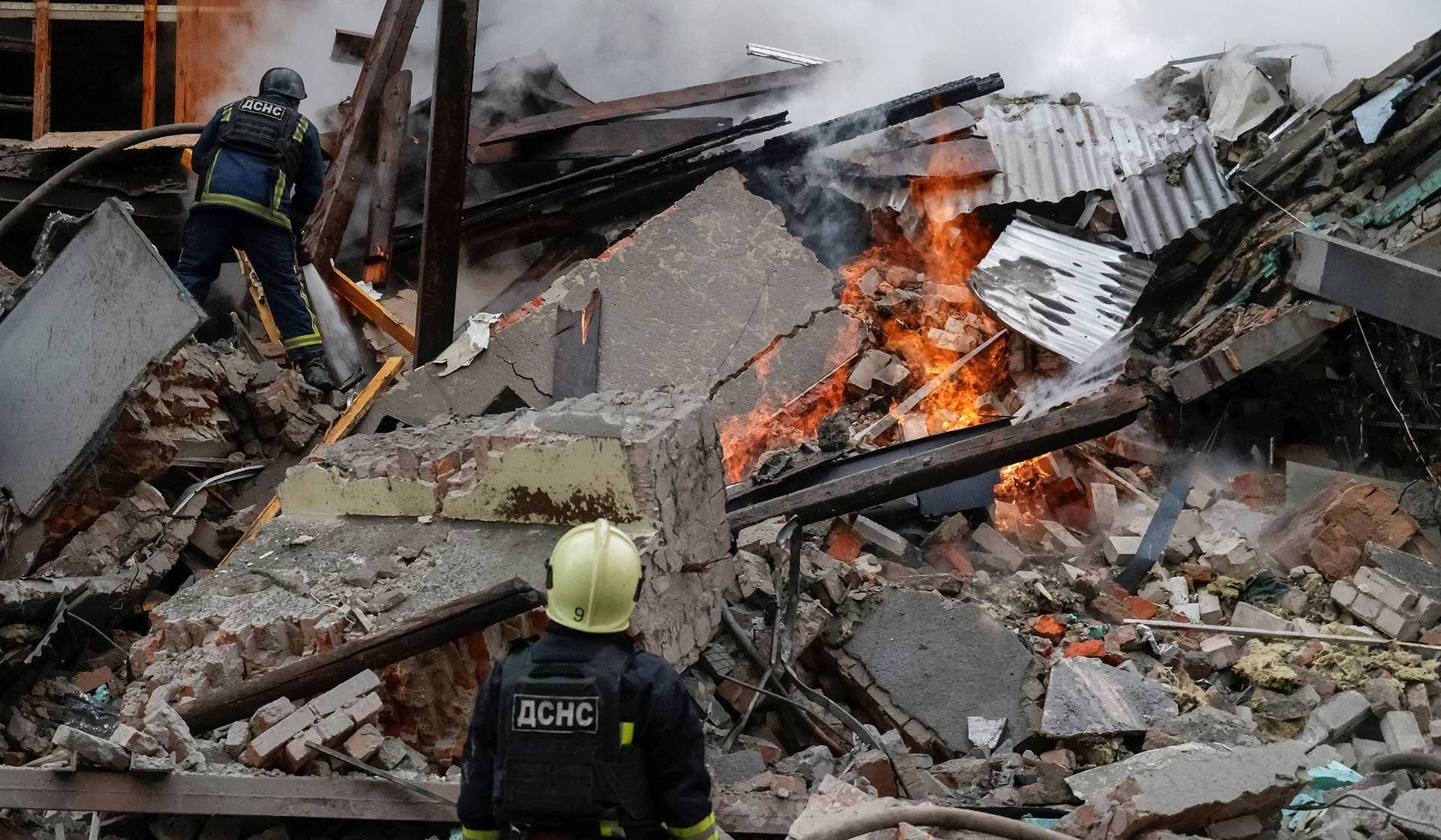 Firefighters work at the site of an apartment building hit by a Russian air strike in Kharkiv