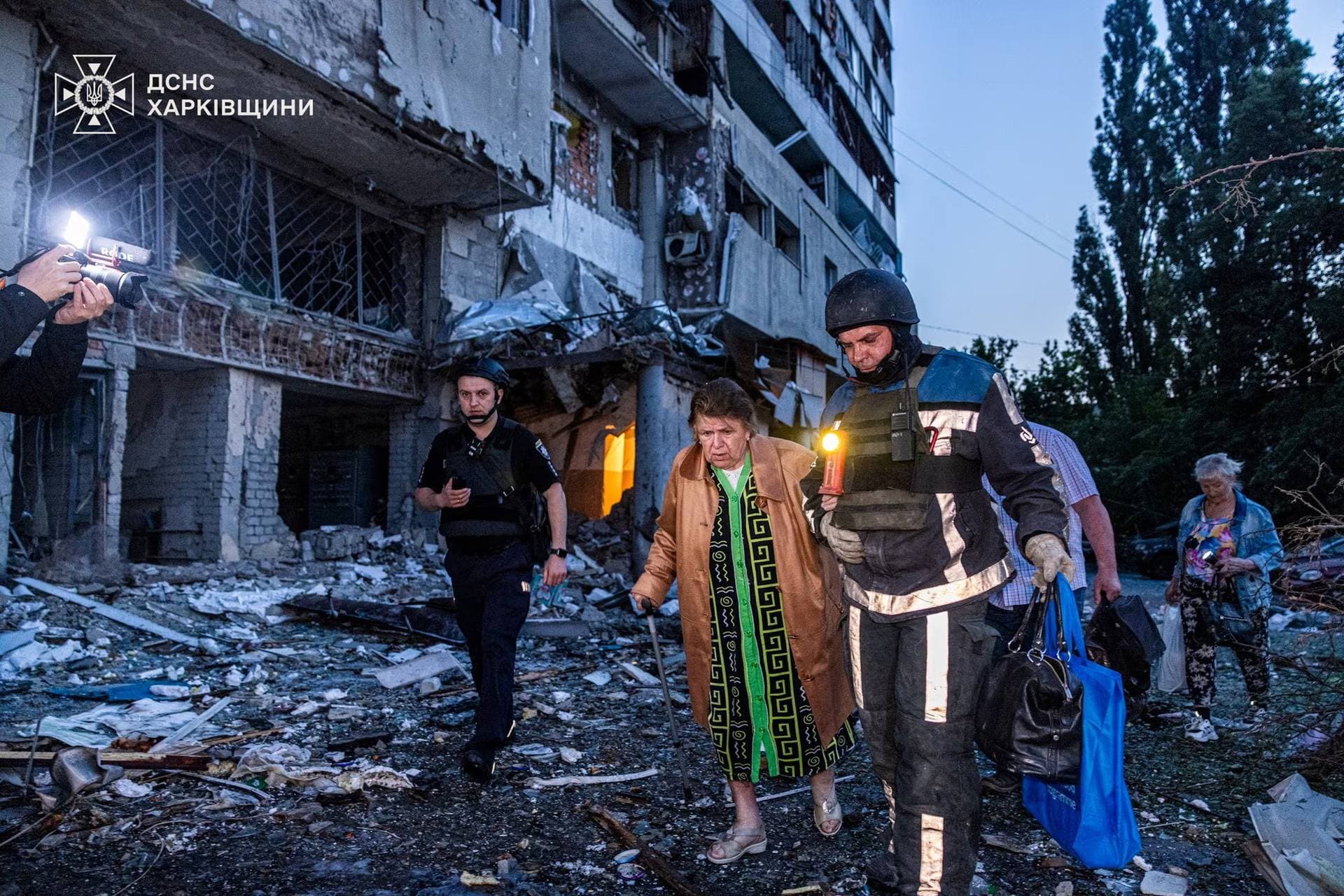 A rescuer assists a woman during an evacuation from apartment building damaged by a Russian drone strike in Kharkiv