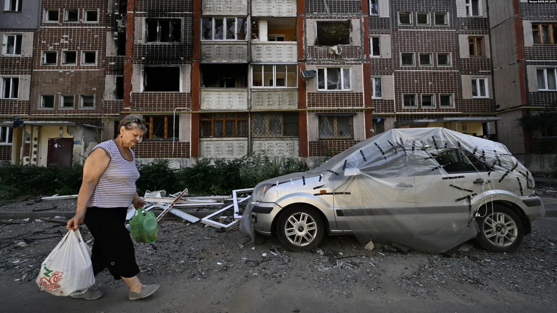 A woman gathers her belongings from a heavily damaged residential building in the Saltivka neighborhood of Kharkiv