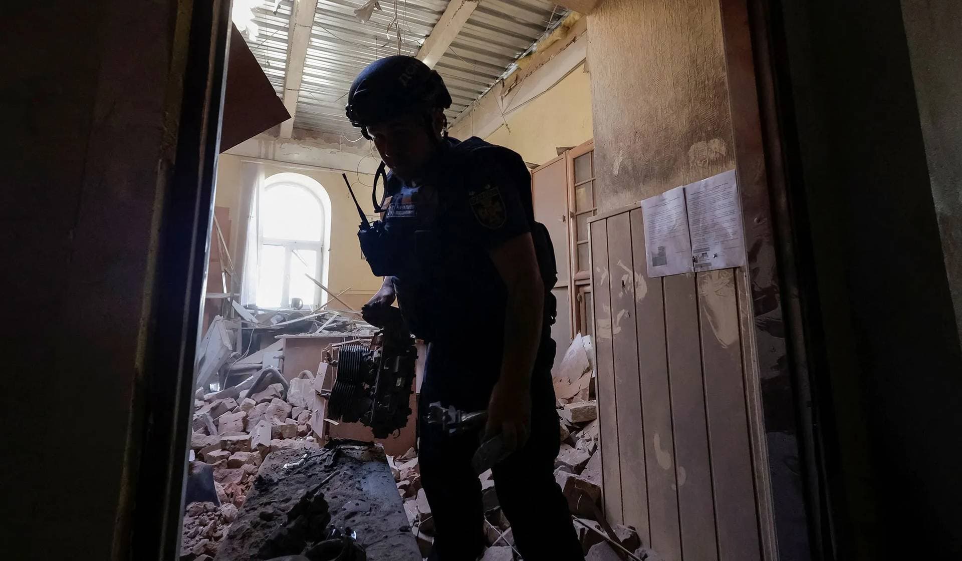 A rescuer holds an engine of Russian drone as he works at the site of a building hit during a Russian drone strike in Kharkiv