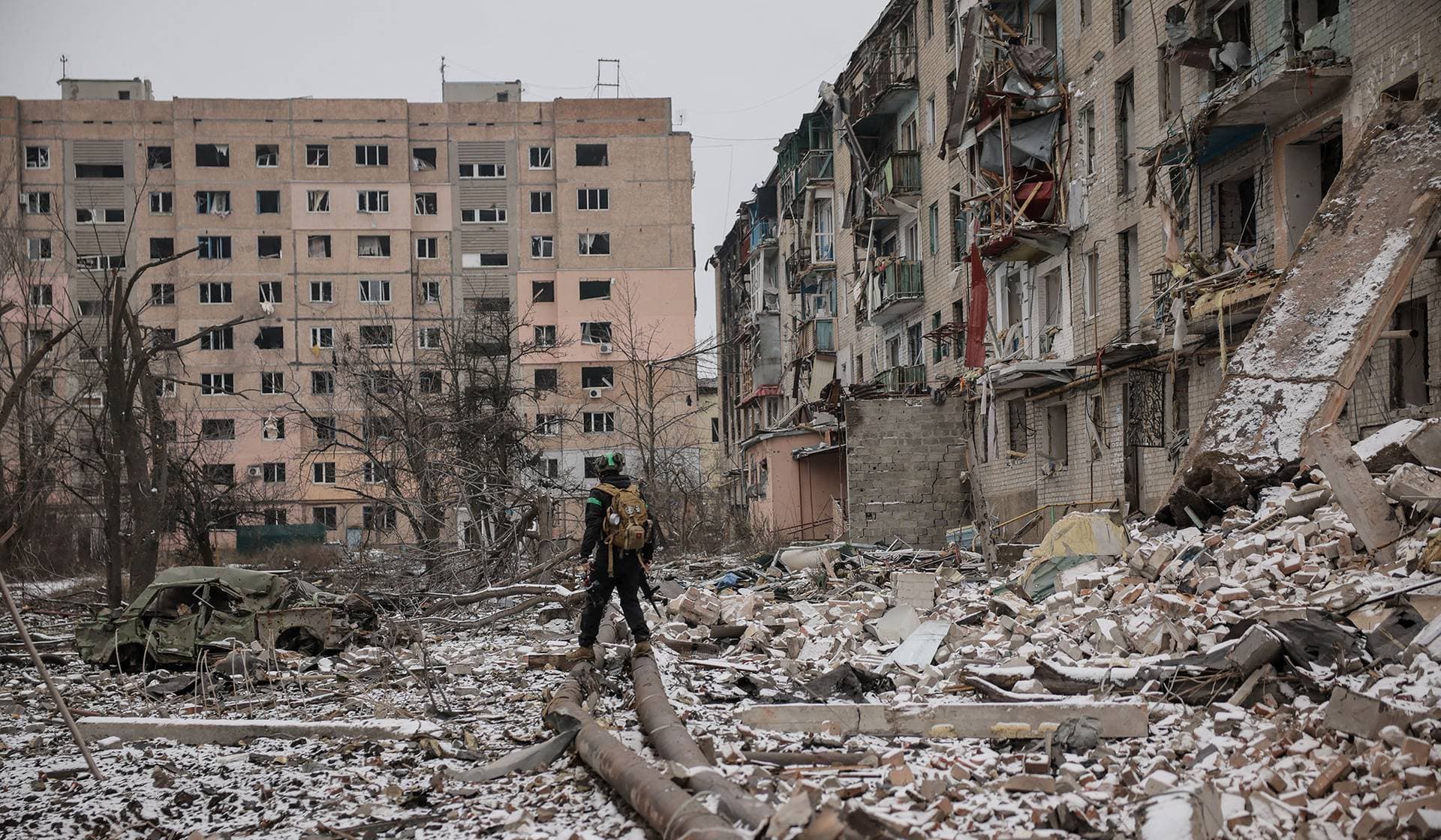 Ukrainian serviceman walks near apartment buildings damaged by Russian military strikes in the frontline town of Kostiantynivka