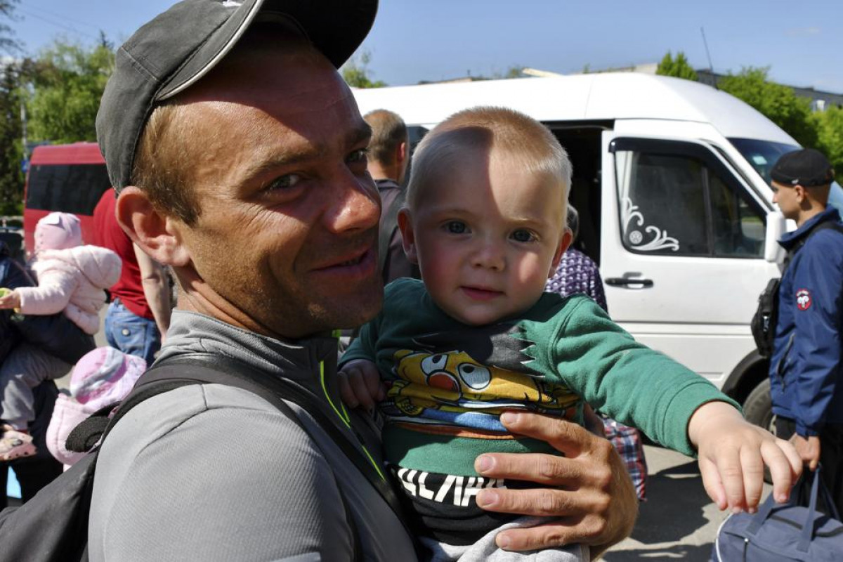 A man holds his son as they wait for boarding during an evacuation of civilians in Kramatorsk