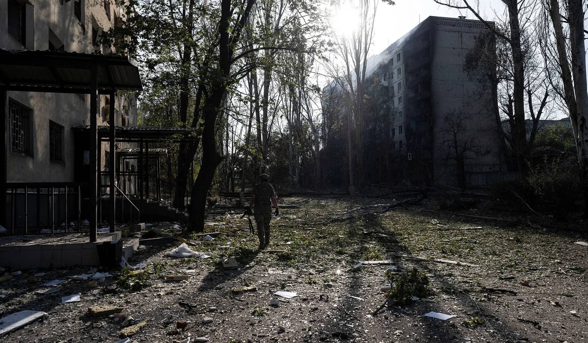 A service member of the Ukrainian Armed Forces walks next to damaged apartment buildings in the frontline town of Kostiantynivka