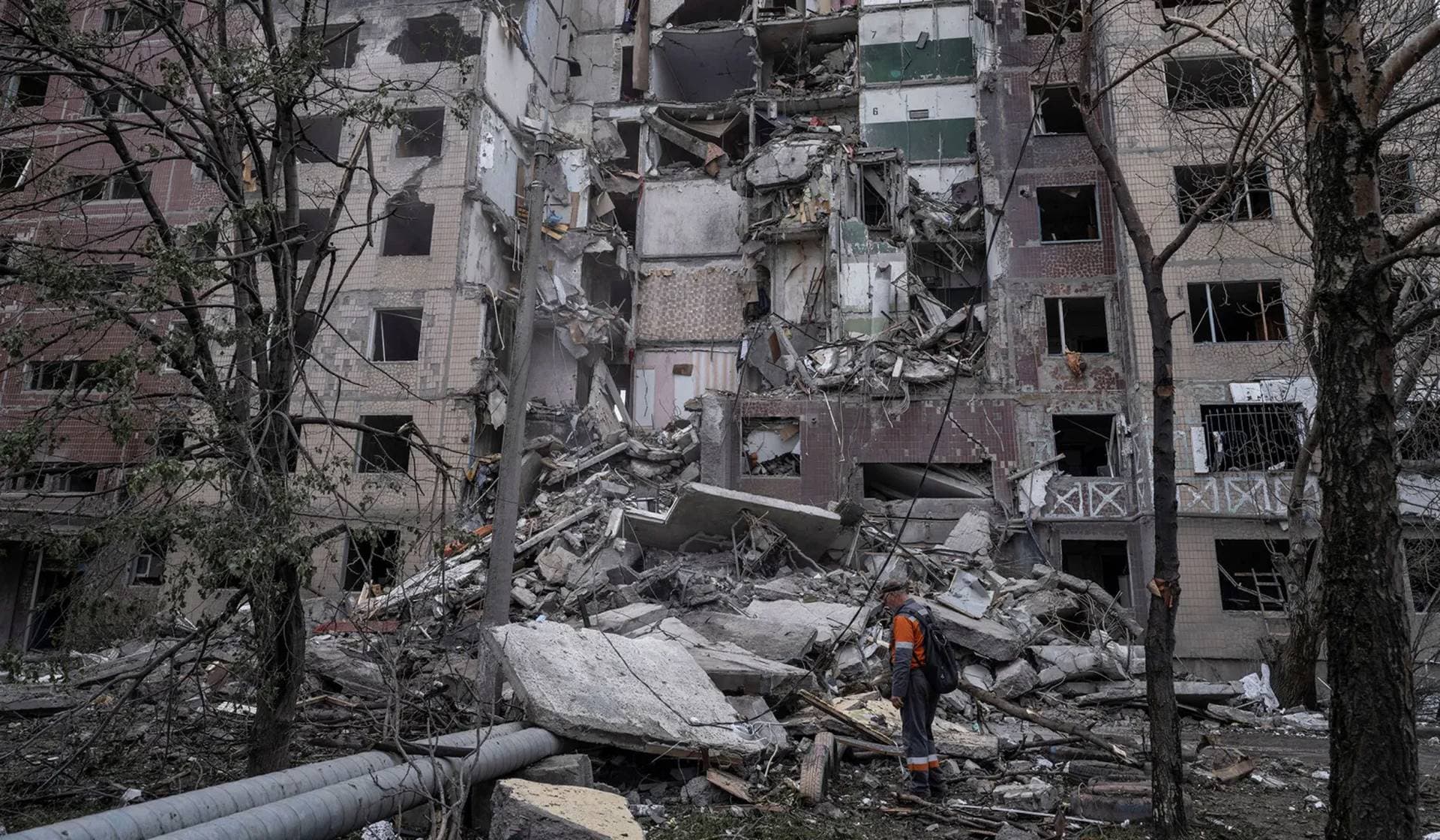 A municipal worker stands in front of an apartment building heavily damaged by a Russian air strike in the frontline town of Kostiantynivka