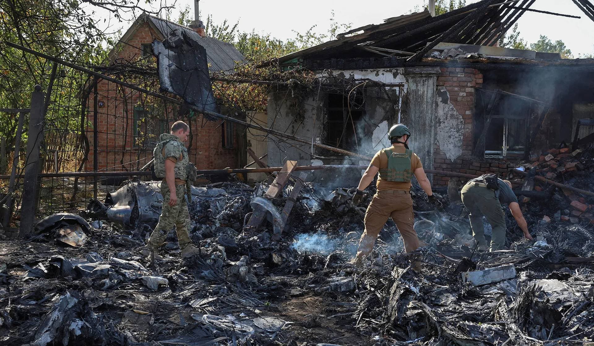Ukrainian service members inspect parts of a Russian aerial vehicle in a residential area of Kostintynivka