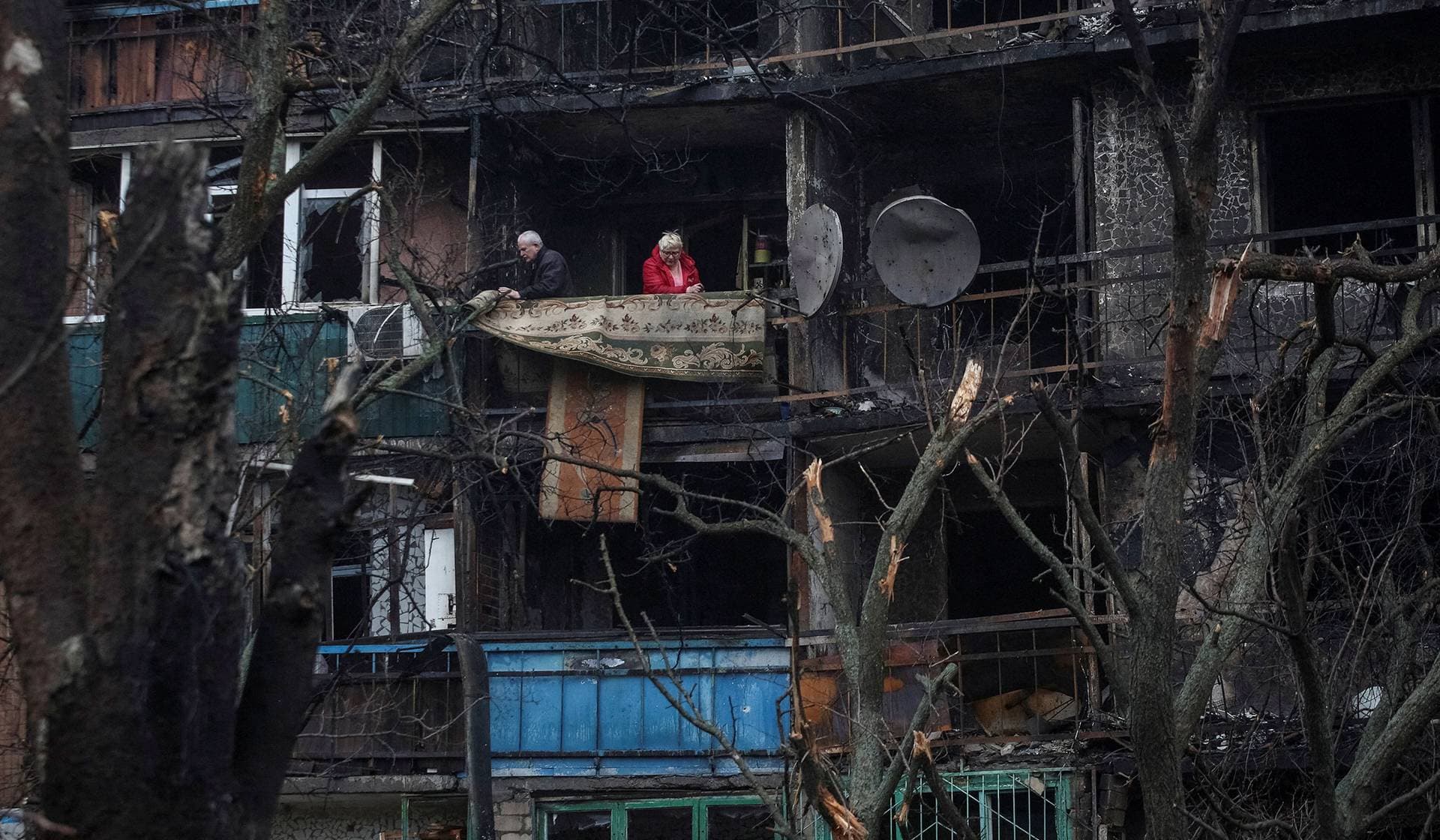 Residents stand at the balcony of their flat in a building damaged by a Russian drone strike, which happened late evening on Monday in Kramatorsk