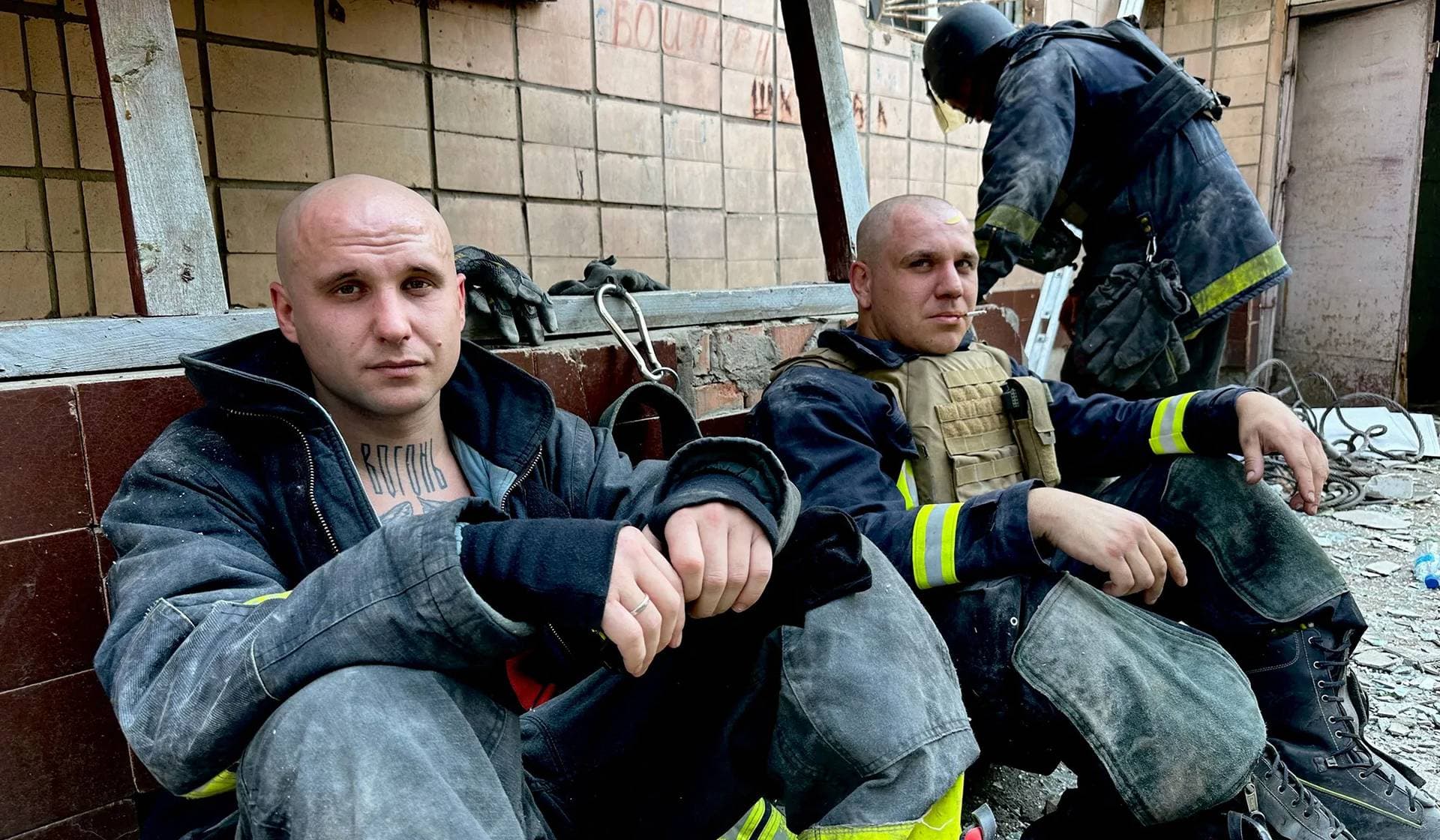 Emergency workers rest near the site where a hotel was hit by a missile in Kramatorsk