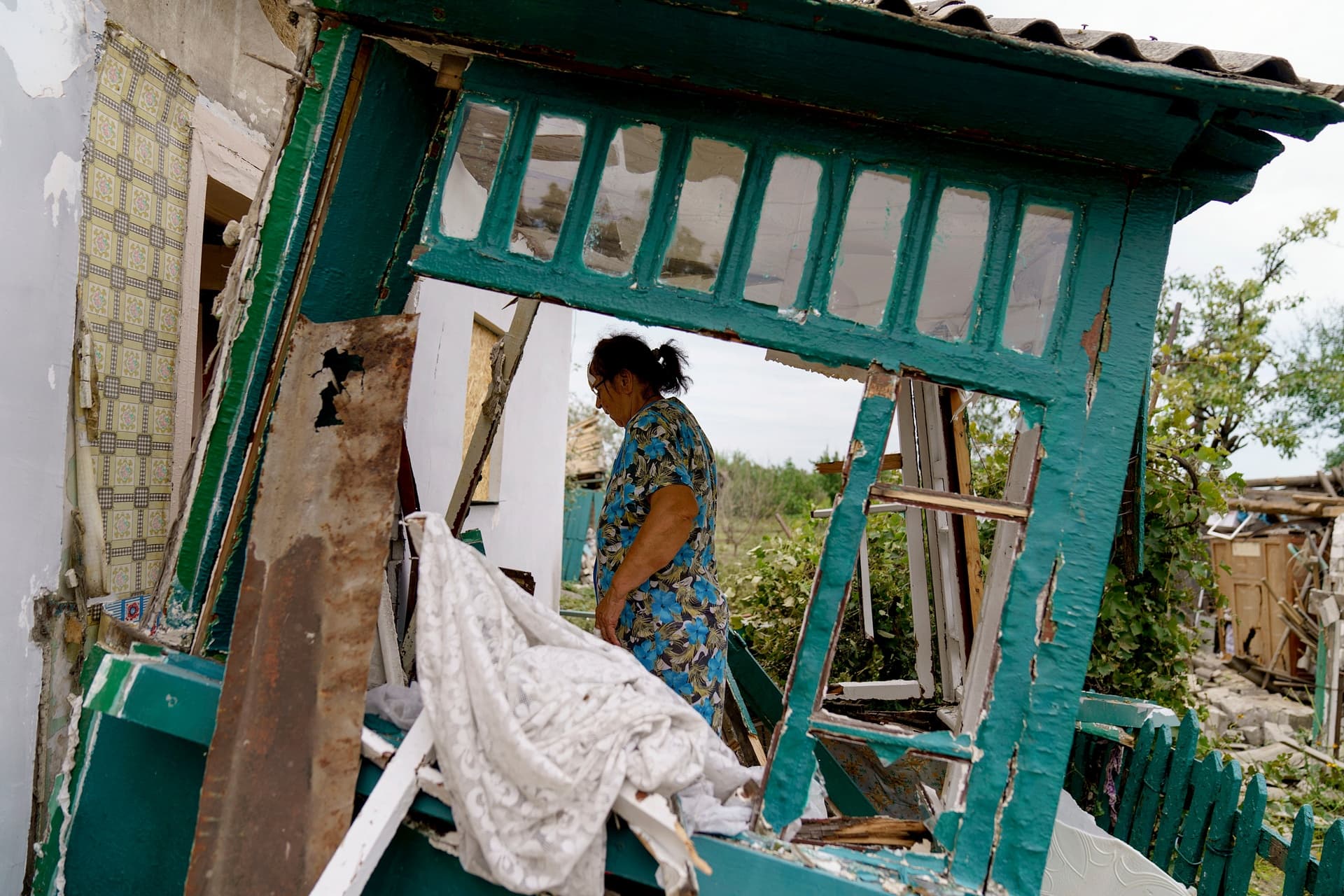 Valentyna Kondratieva walks into her damaged home in Kramatorsk