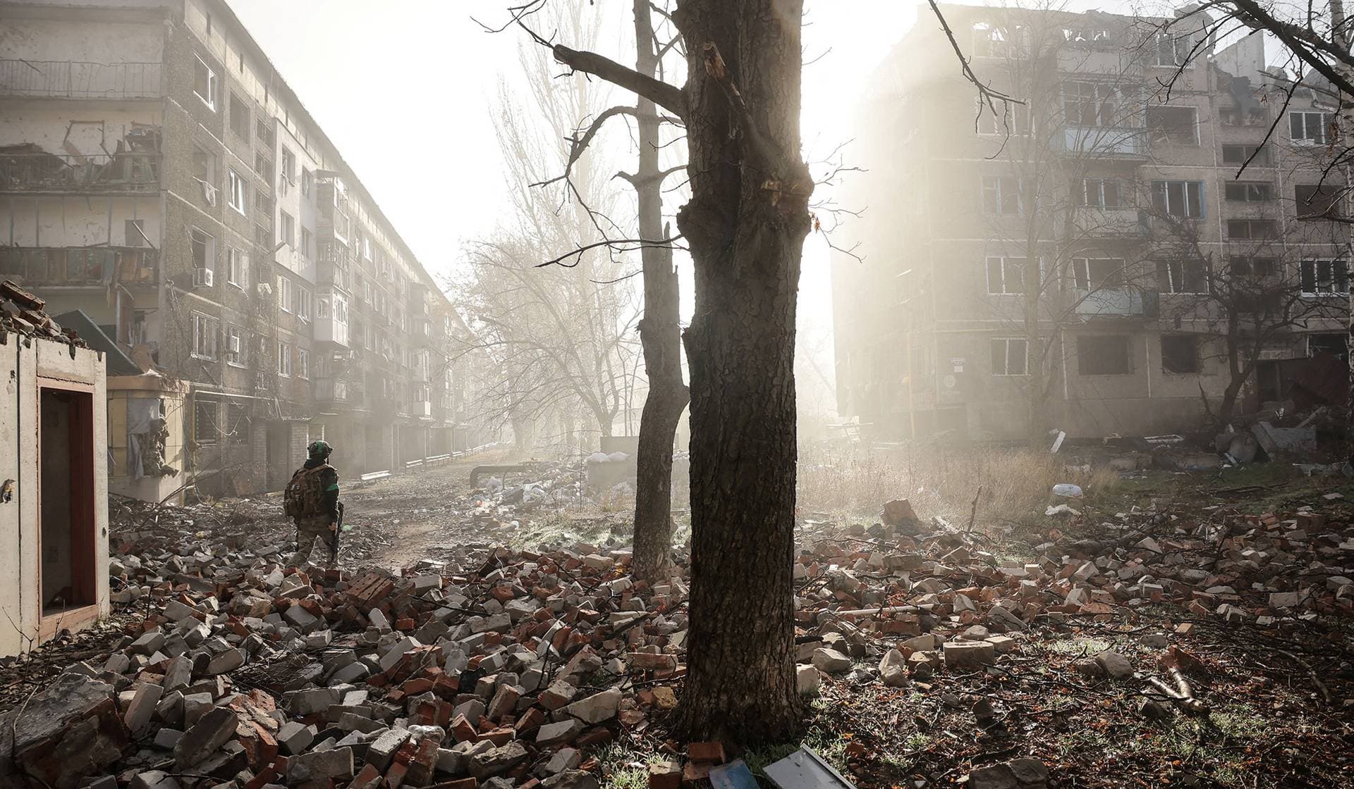 A Ukrainian serviceman walks near apartment buildings damaged by a Russian military strike in the frontline town of Kostiantynivka