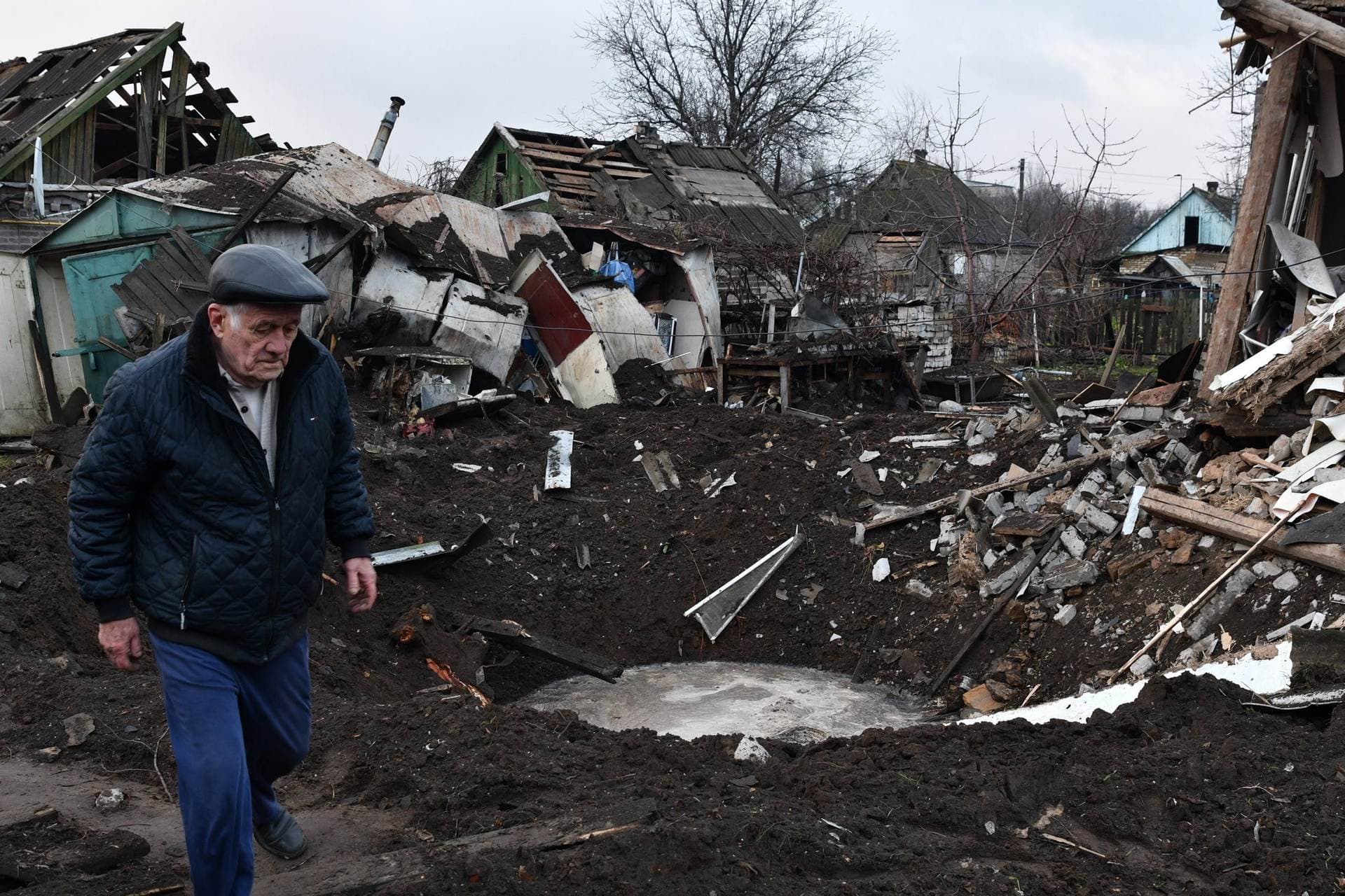 A man walks near a crater and his house that was damaged after Russian shelling in Kramatorsk
