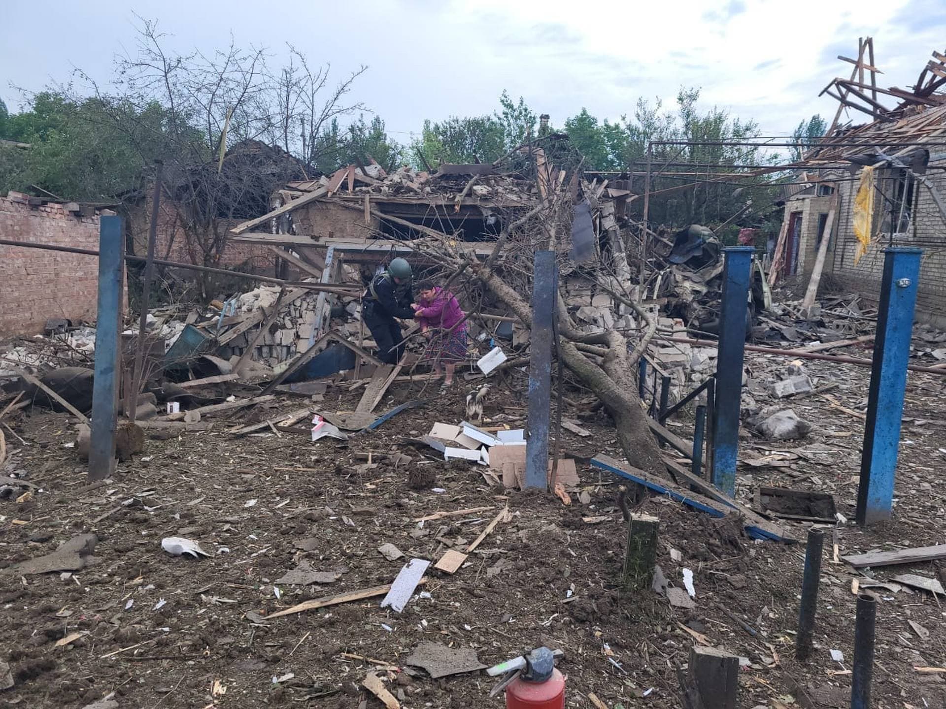 A Ukrainian police officer helps a local resident to leave her house ruined in the deadly morning Russian rocket attack in Kostyantynivka