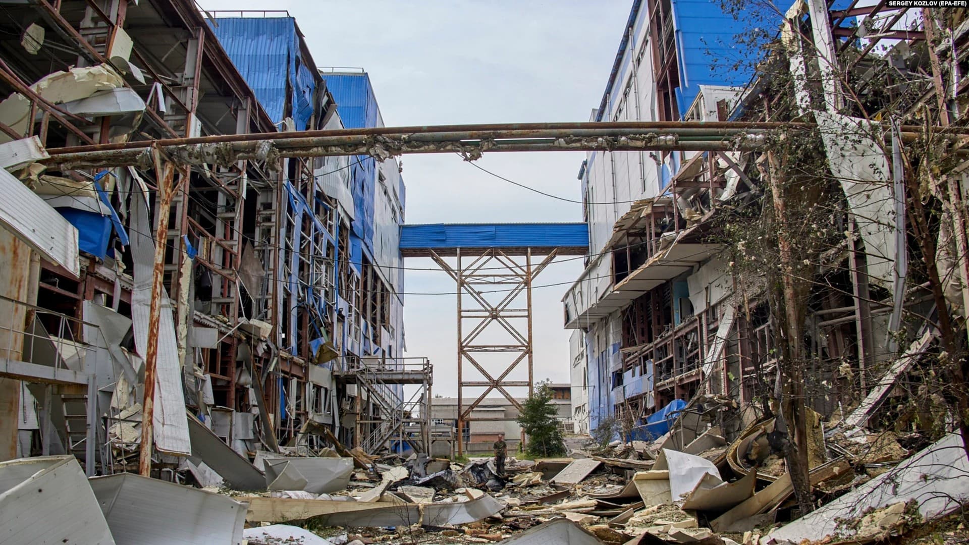 A man walks through a damaged factory complex after a rocket attack in Merefa
