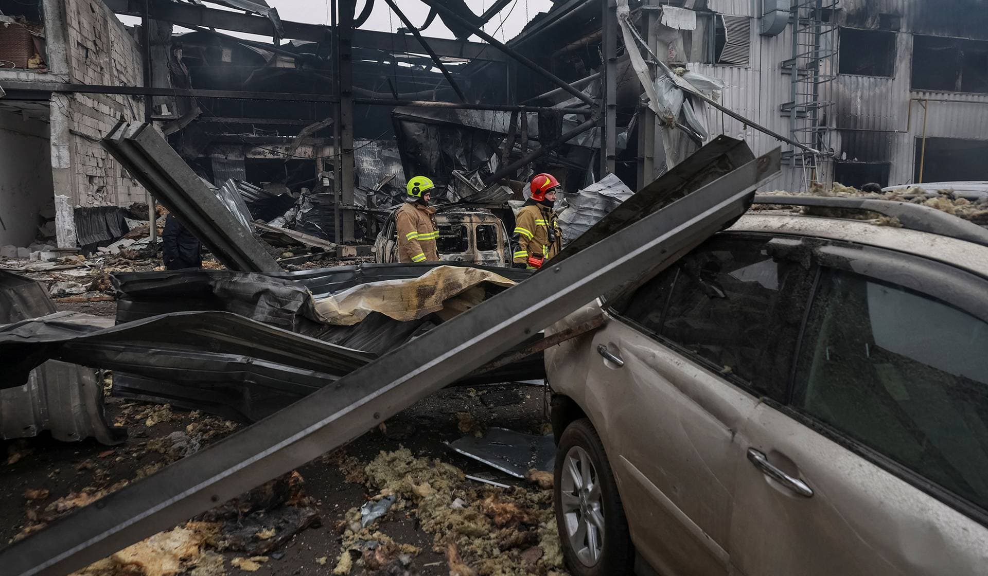 Rescuers walk near damaged cars at the site of a Russian drone strike in Odesa