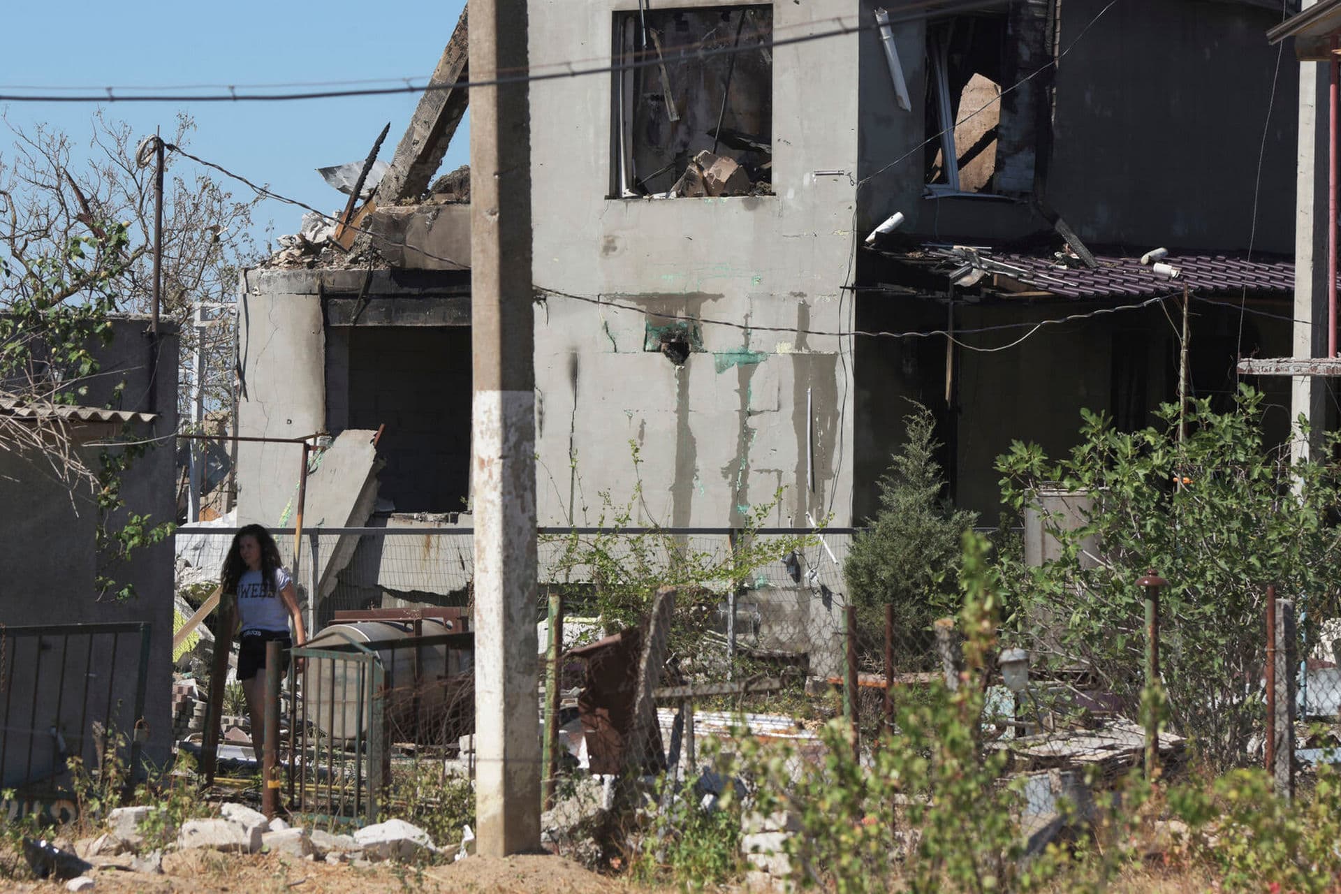 A woman walks in a yard of a apartment building destroyed by Russian shelling on the outskirts of Odesa