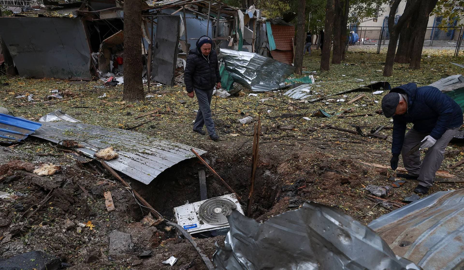 Residents search for parts of a Russian kamikaze drone at a site of a strike in Odesa
