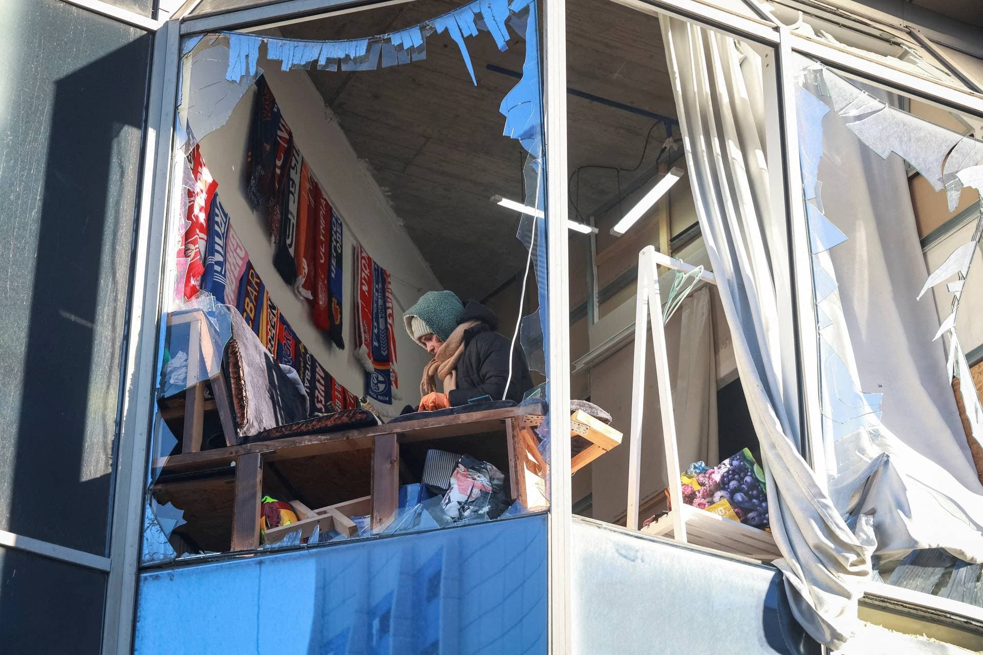 A woman appears in a broken window of a building hit by a Russian drone strike in Odesa, Ukraine, February 9, 2026.