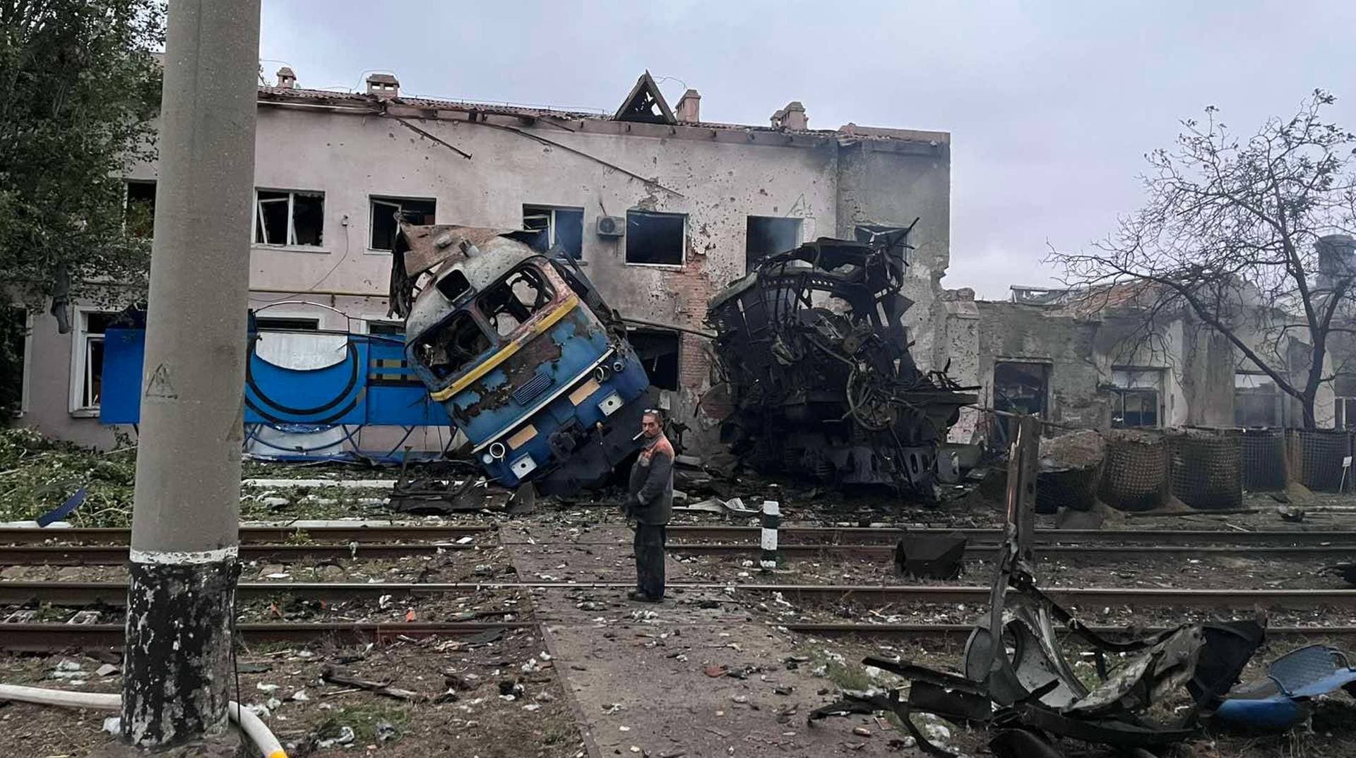 A railway employee stands next to a destroyed train at the compound of a depot after it was hit during an overnight Russian drone strike in Odesa