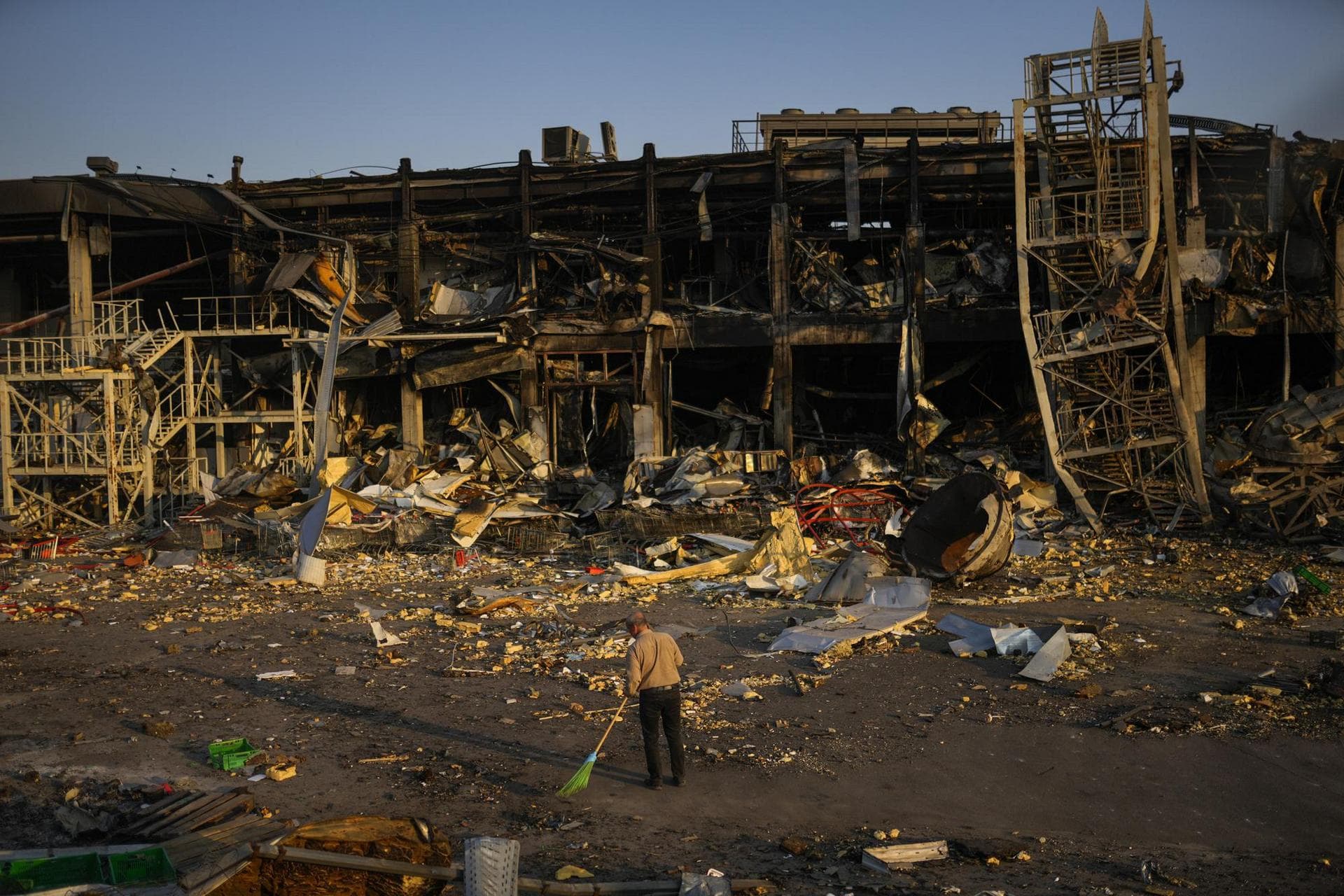 A man sweeps rubble next to a shopping and entertainment mall in Odessa