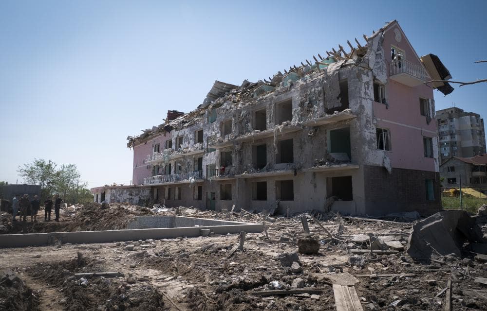 Local officials stand in front of a damaged residential building in the town of Serhiivka, located about 50 kilometers southwest of Odesa