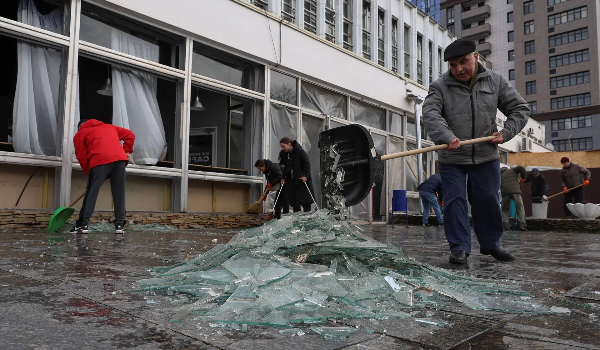Local residents collect glass from broken windows at a site of a Russian missile strike in Odesa