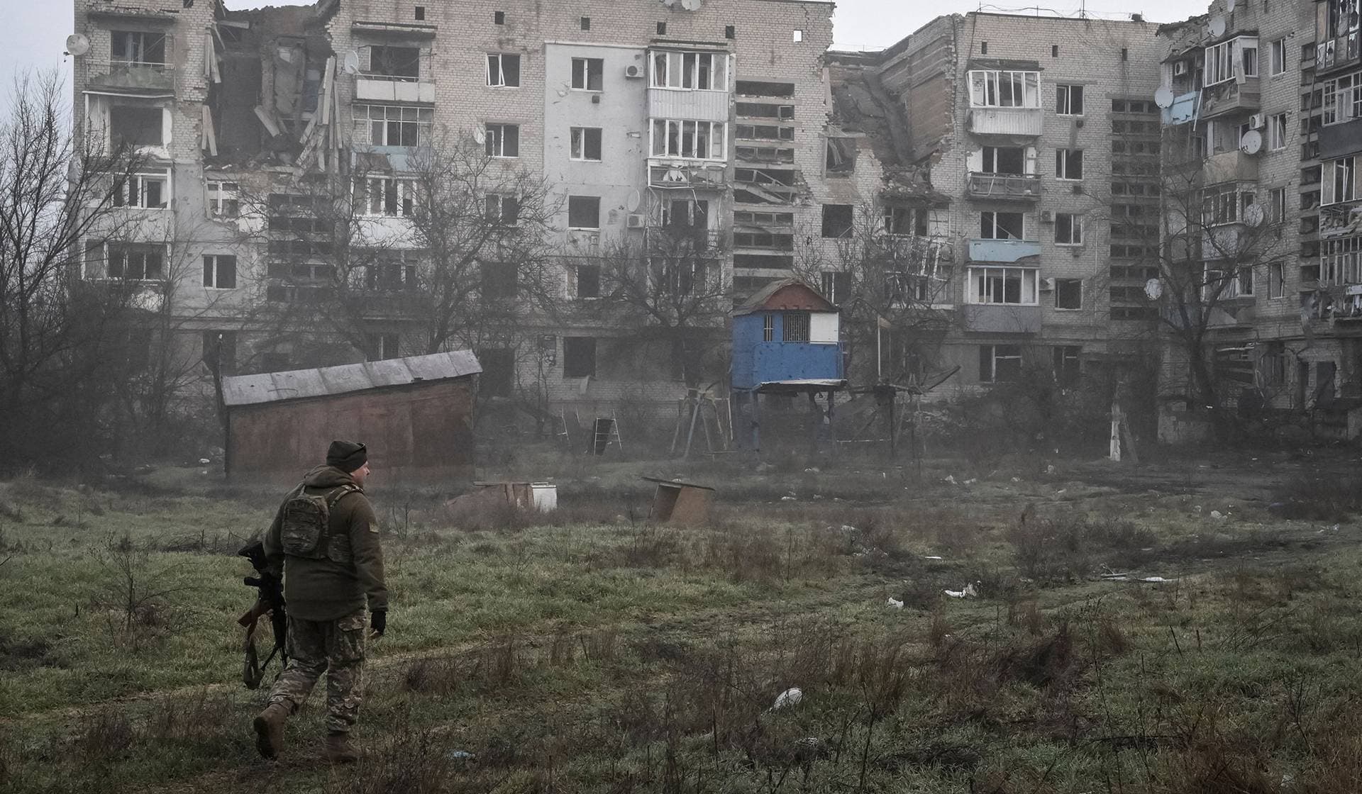A Ukrainian service member walks near residential buildings damaged by Russian military strikes in the frontline town Orikhiv